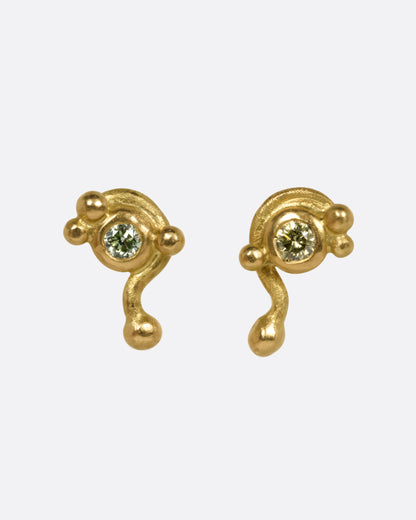 A pair of yellow gold drip stud earrings with green diamonds, shown from the front.