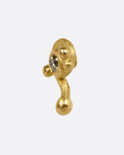 A yellow gold drip stud earring with a green diamond, shown from the side.
