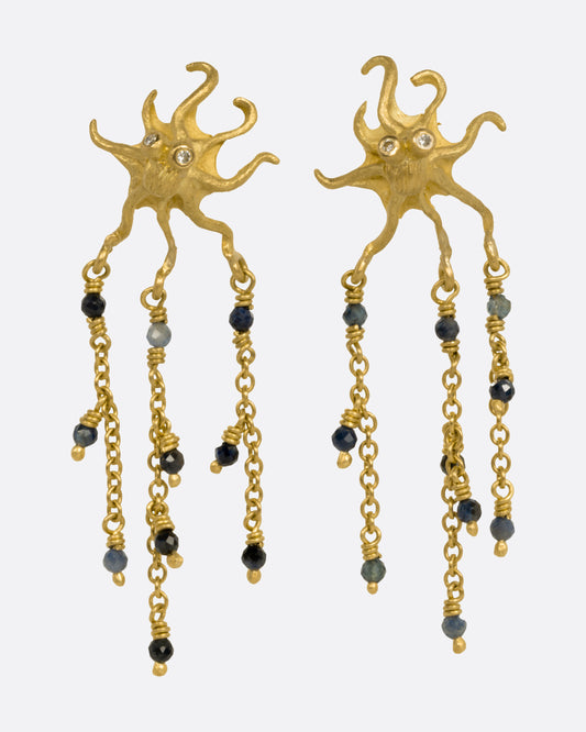 A pair of yellow gold octopus earrings with cascading chain fringe, sapphire beads, and diamond-eyes, shown from the front.