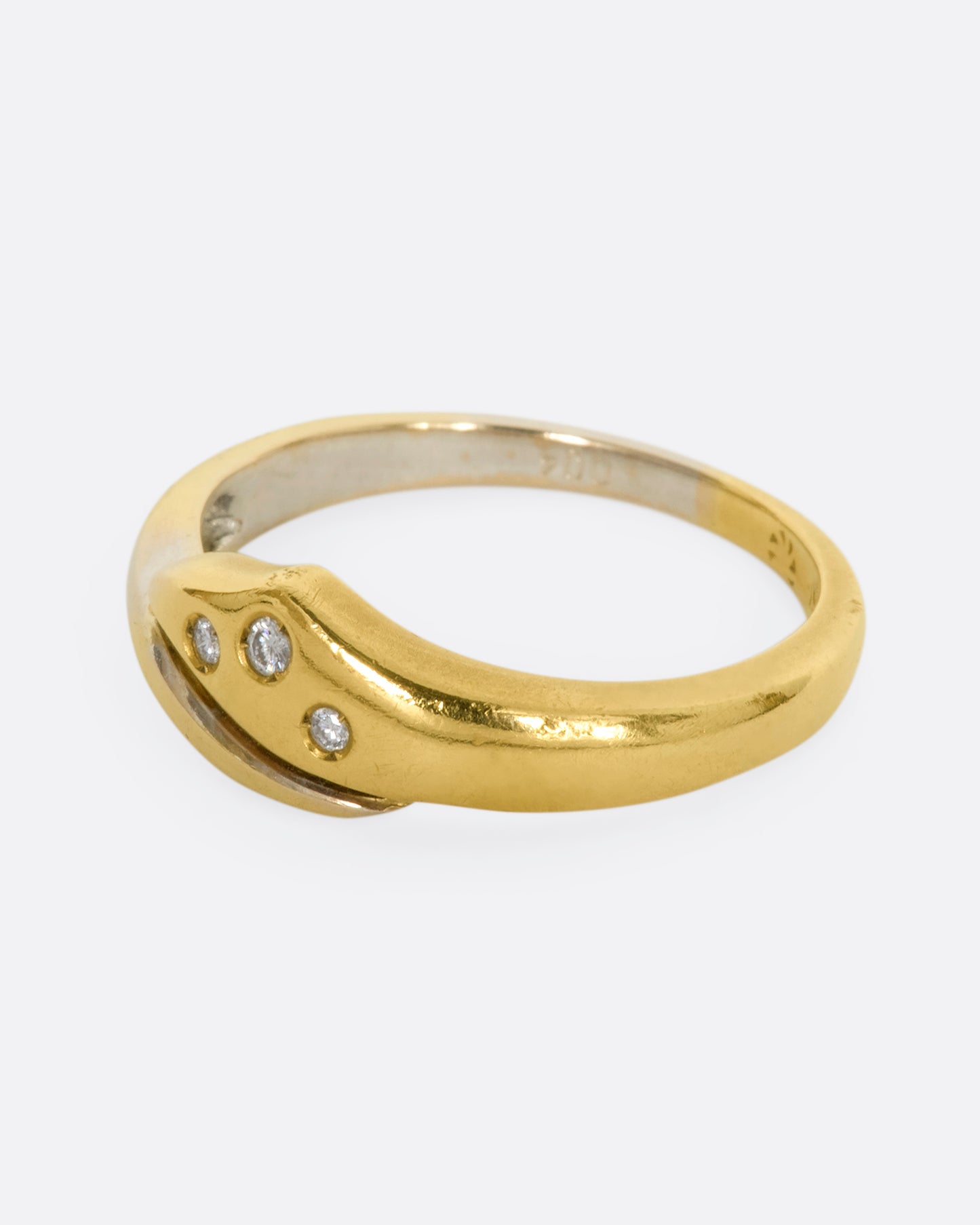 A yellow and white gold wrap ring with three diamonds. Shown from the side.