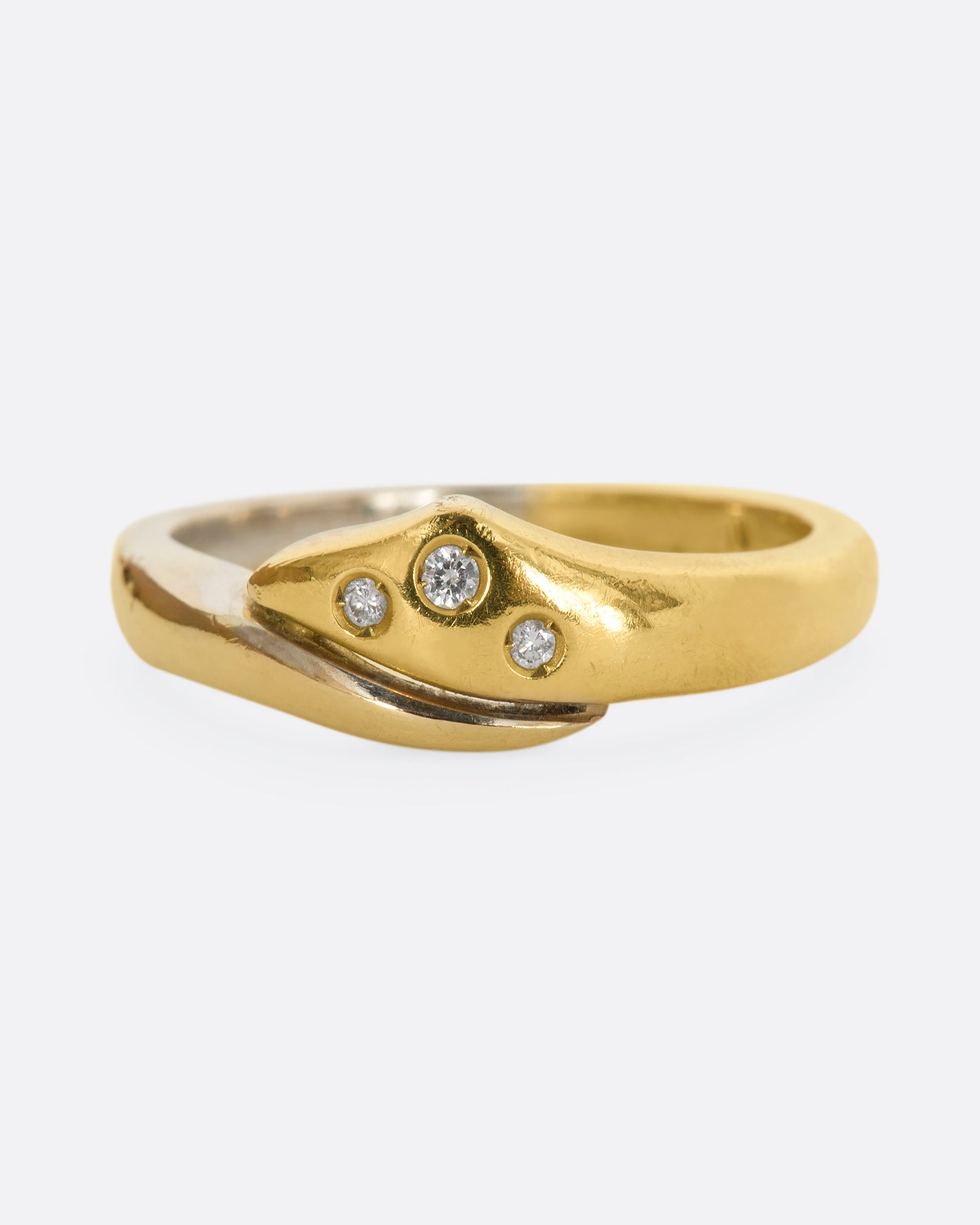 A yellow and white gold wrap ring with three diamonds. Shown from the front.