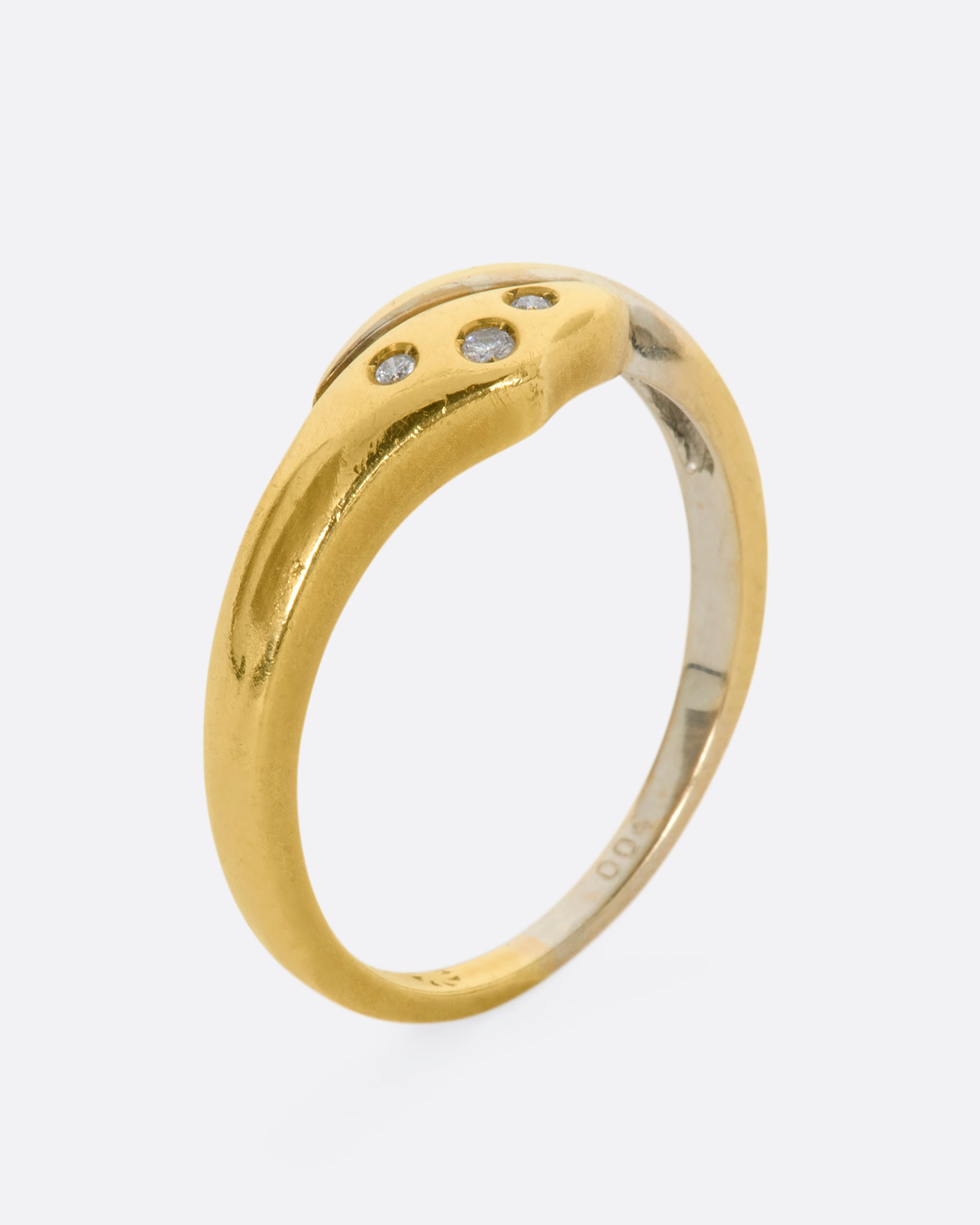 A yellow and white gold wrap ring with three diamonds. Shown from the side, standing up.