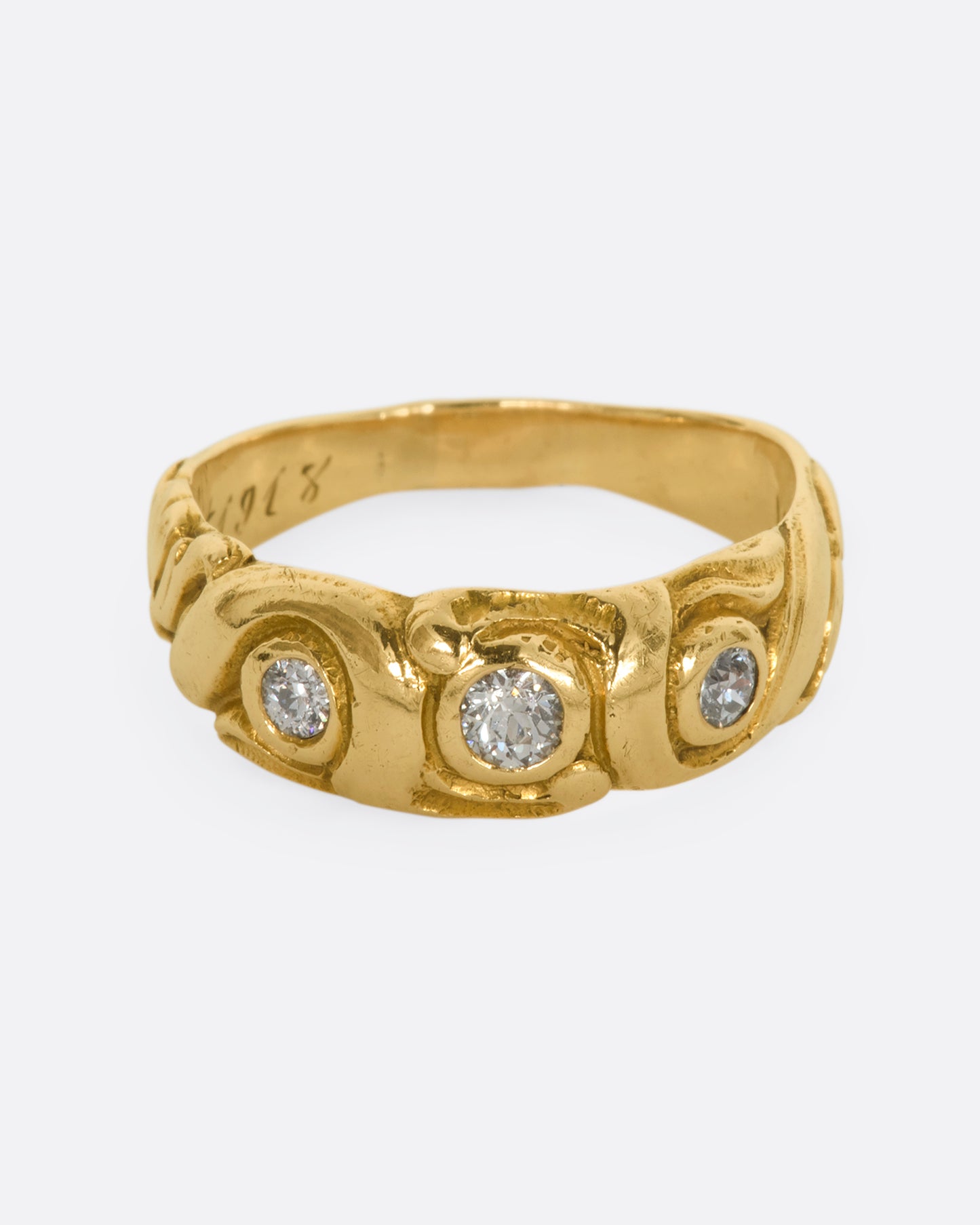 A textured yellow gold ring with three diamonds. View from the front from slightly above.