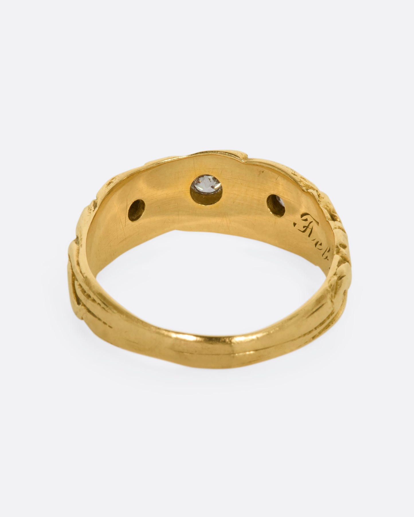 A textured yellow gold ring with three diamonds. View from the back.