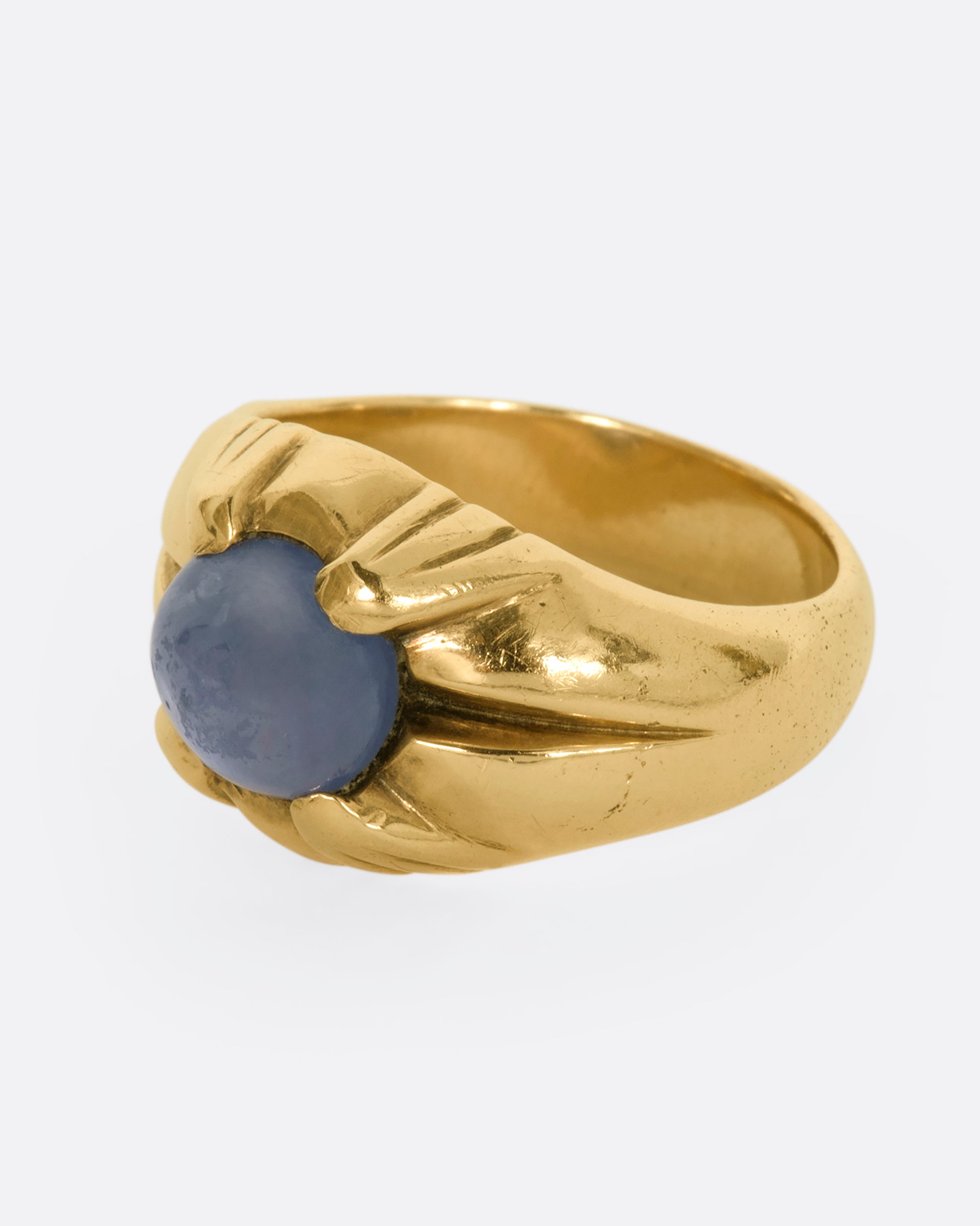 A yellow gold ring with a prong set star sapphire. View from the side.