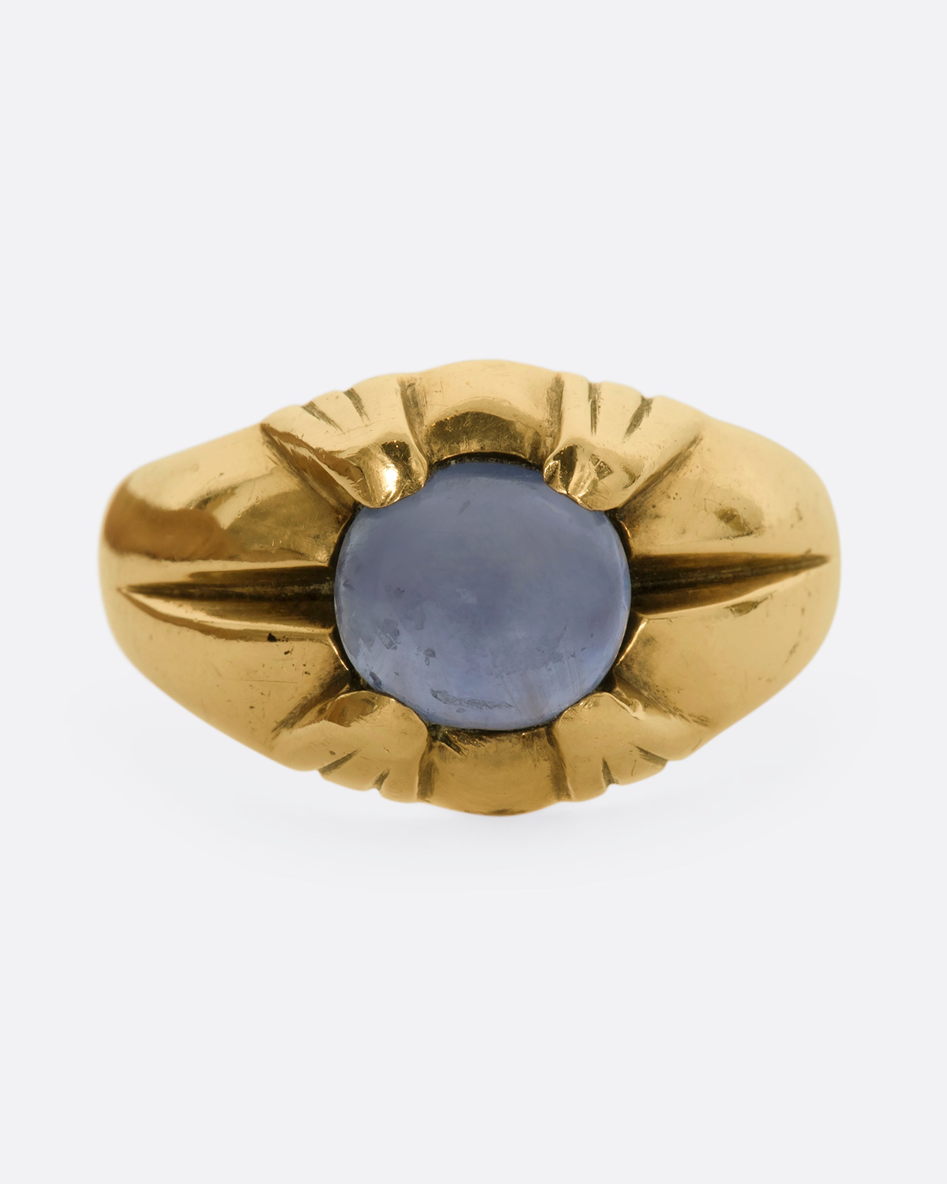 A yellow gold ring with a prong set star sapphire. View from the front close up.