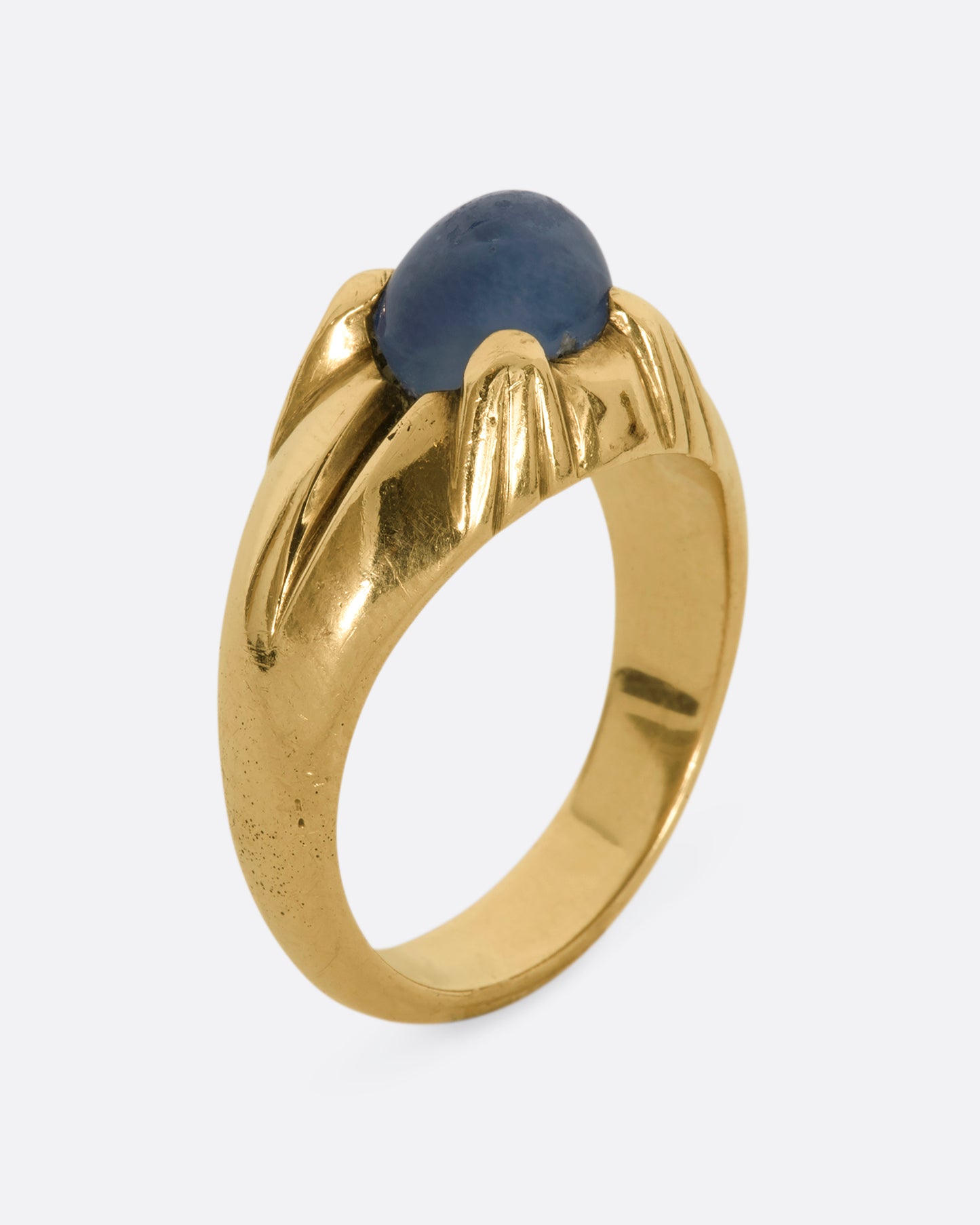 A yellow gold ring with a prong set star sapphire. View standing from the side.