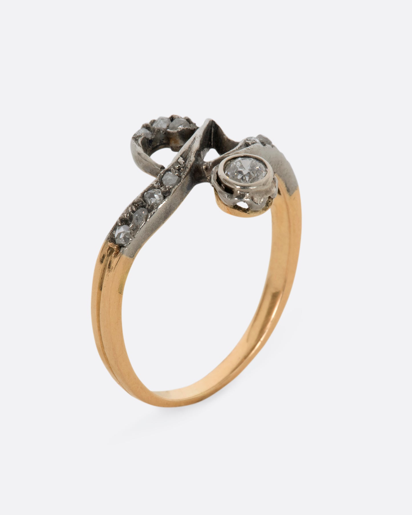 A white and rose gold diamond encrusted abstract ring. View from the side standing up.