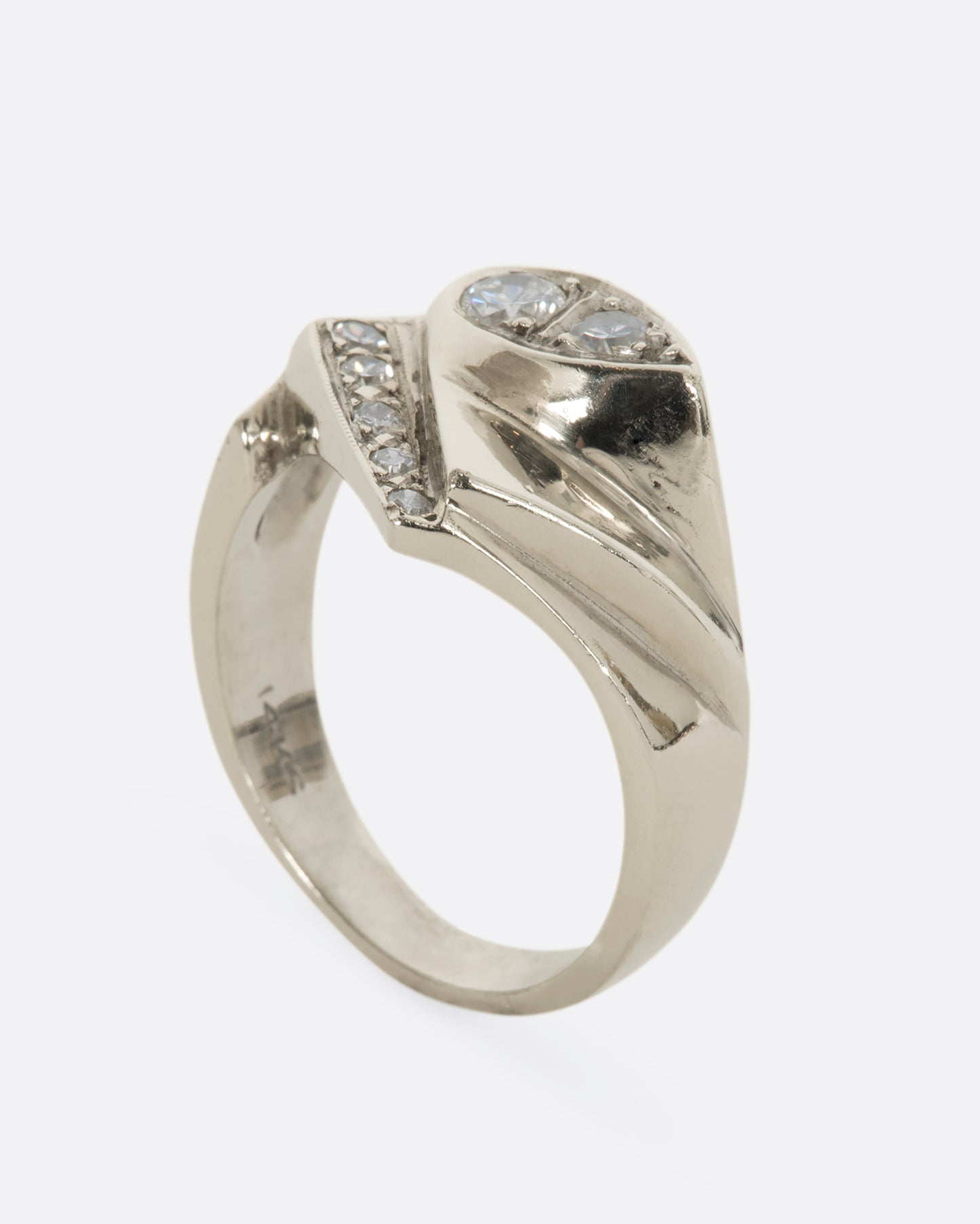 A white gold asymmetrical geometric band with diamonds. View from the side, standing up.