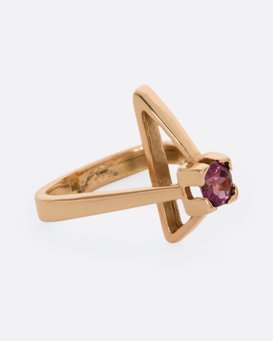 A geometric rose gold ring with a prong set pink tourmaline. Shown from the side.