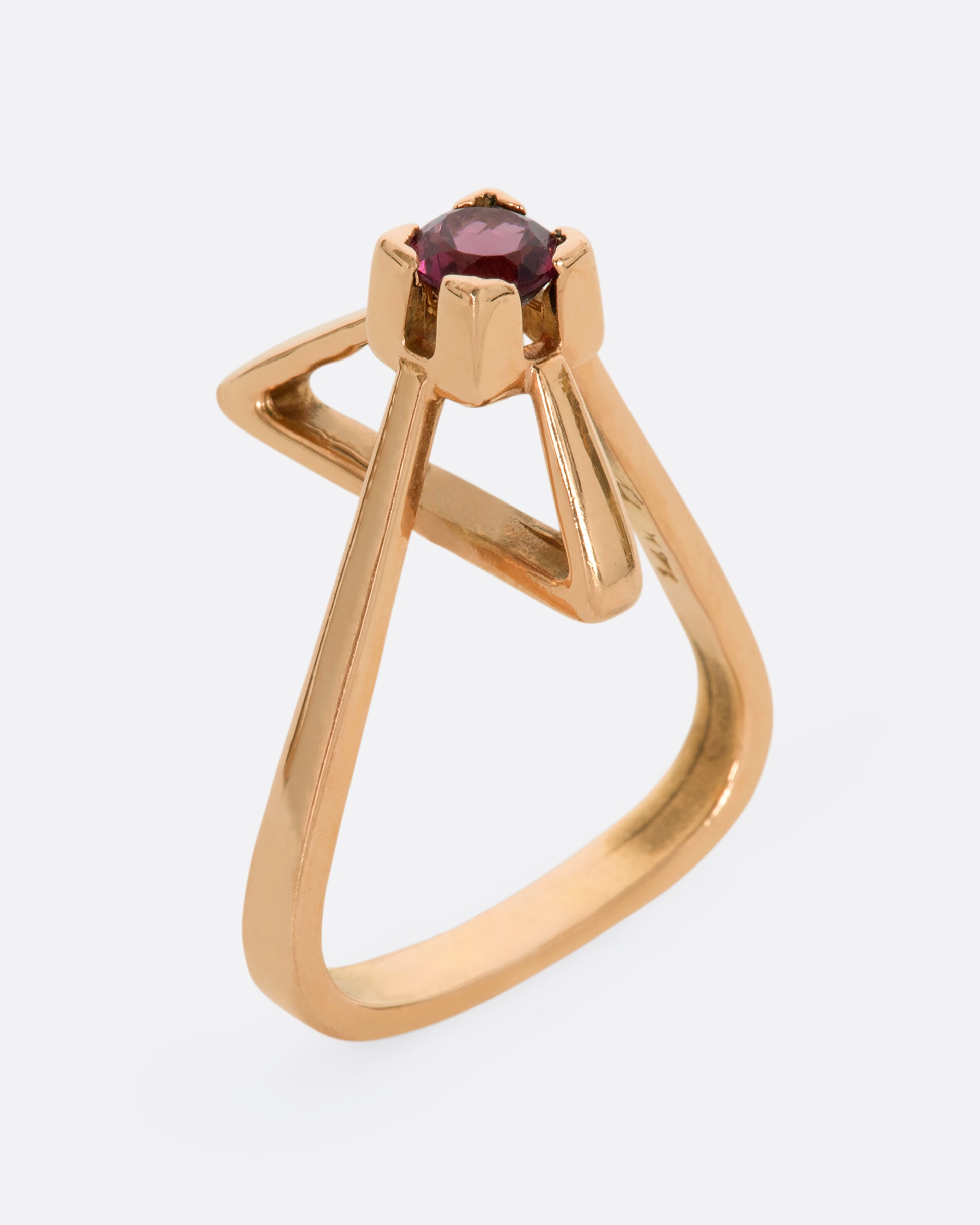 A geometric rose gold ring with a prong set pink tourmaline. Shown from the side, standing up.