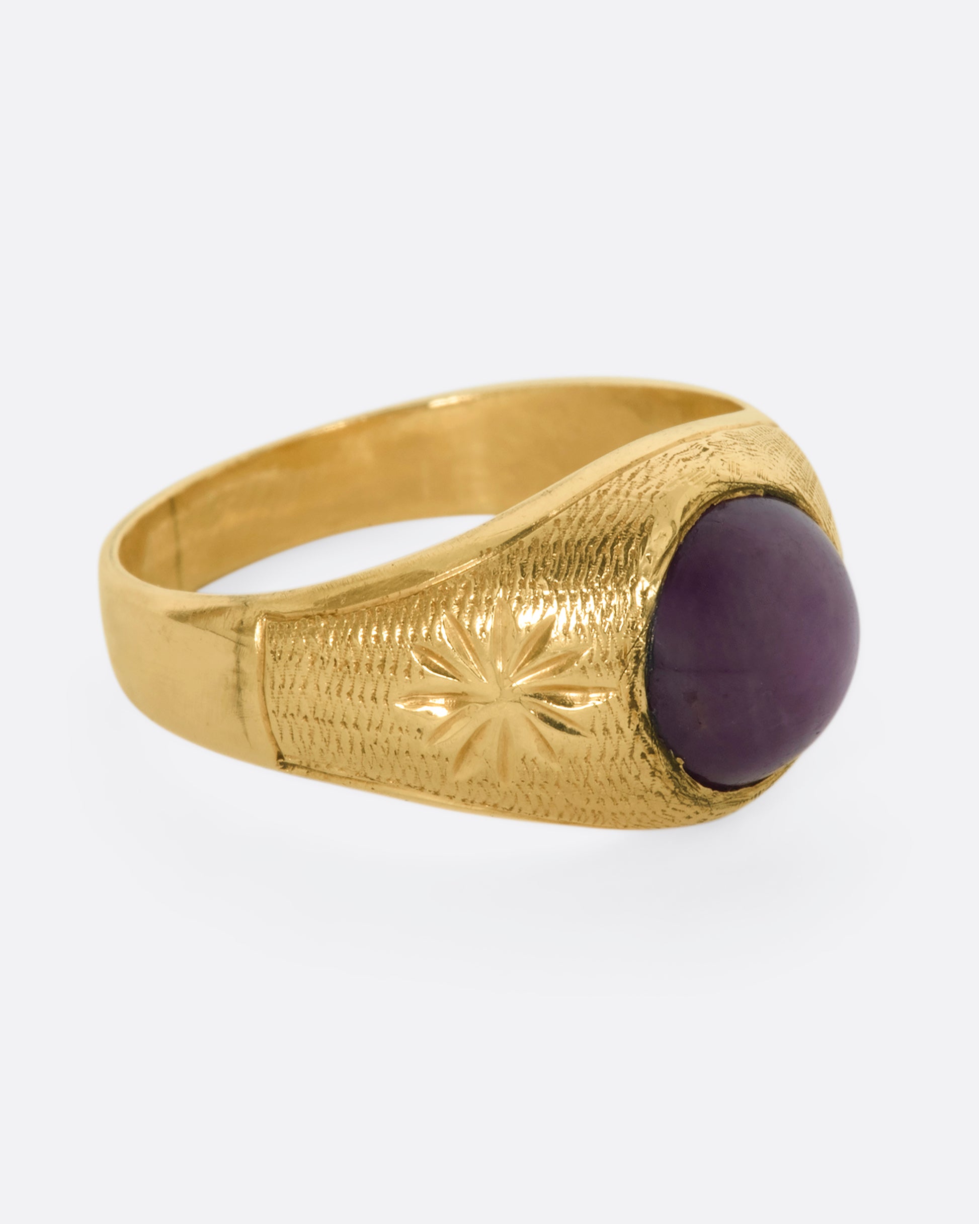 A domed yellow gold vintage ring with a ruby cabochon and starflower details. View from the alternate side.