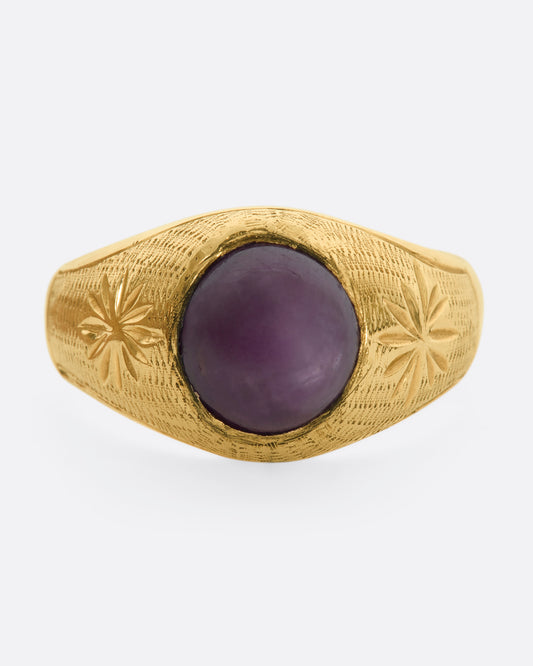 A domed yellow gold vintage ring with a ruby cabochon and starflower details. View from the front.