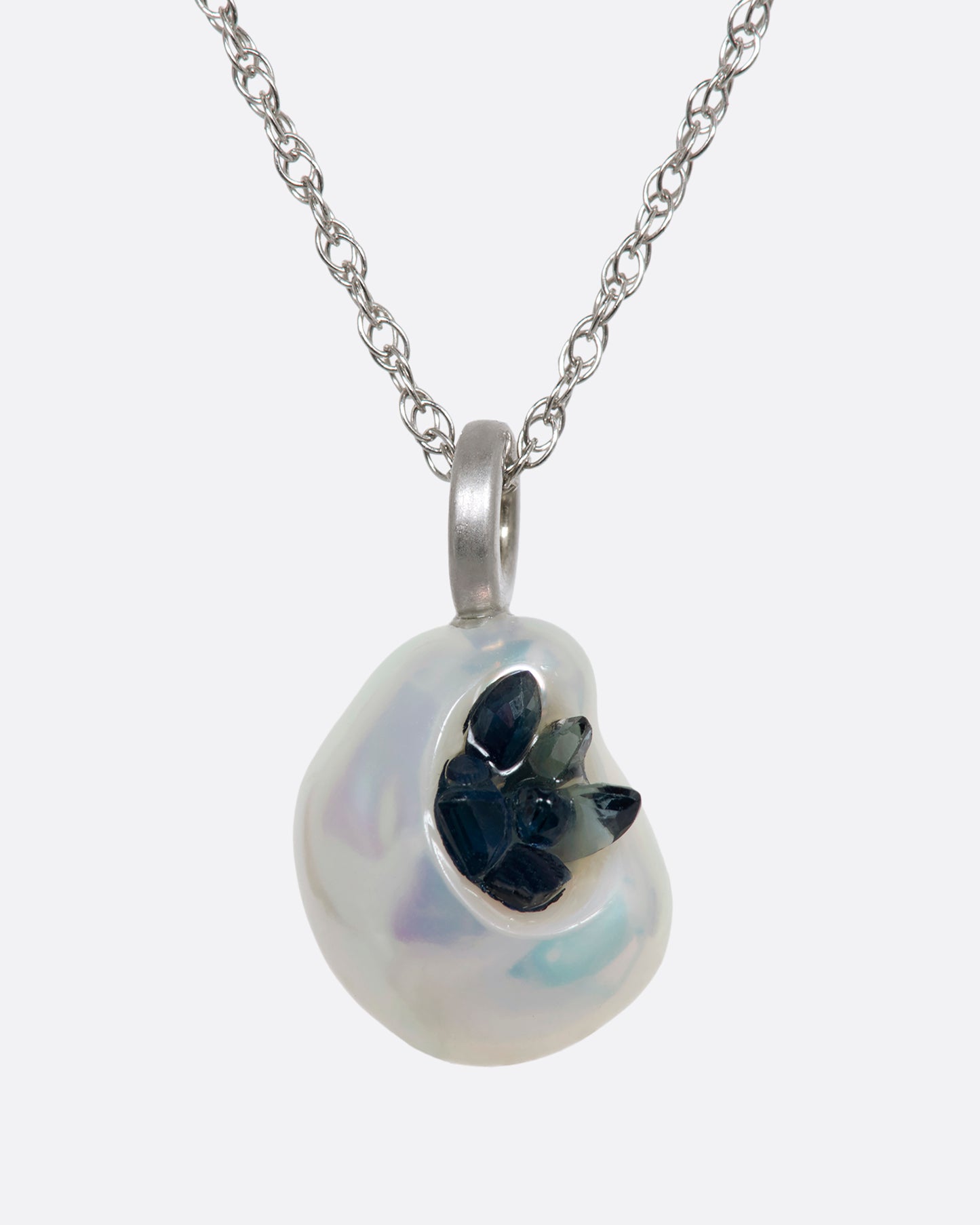 A white keshi pearl pendant filled with reclaimed sapphires hanging on a white gold chain. View from the front.