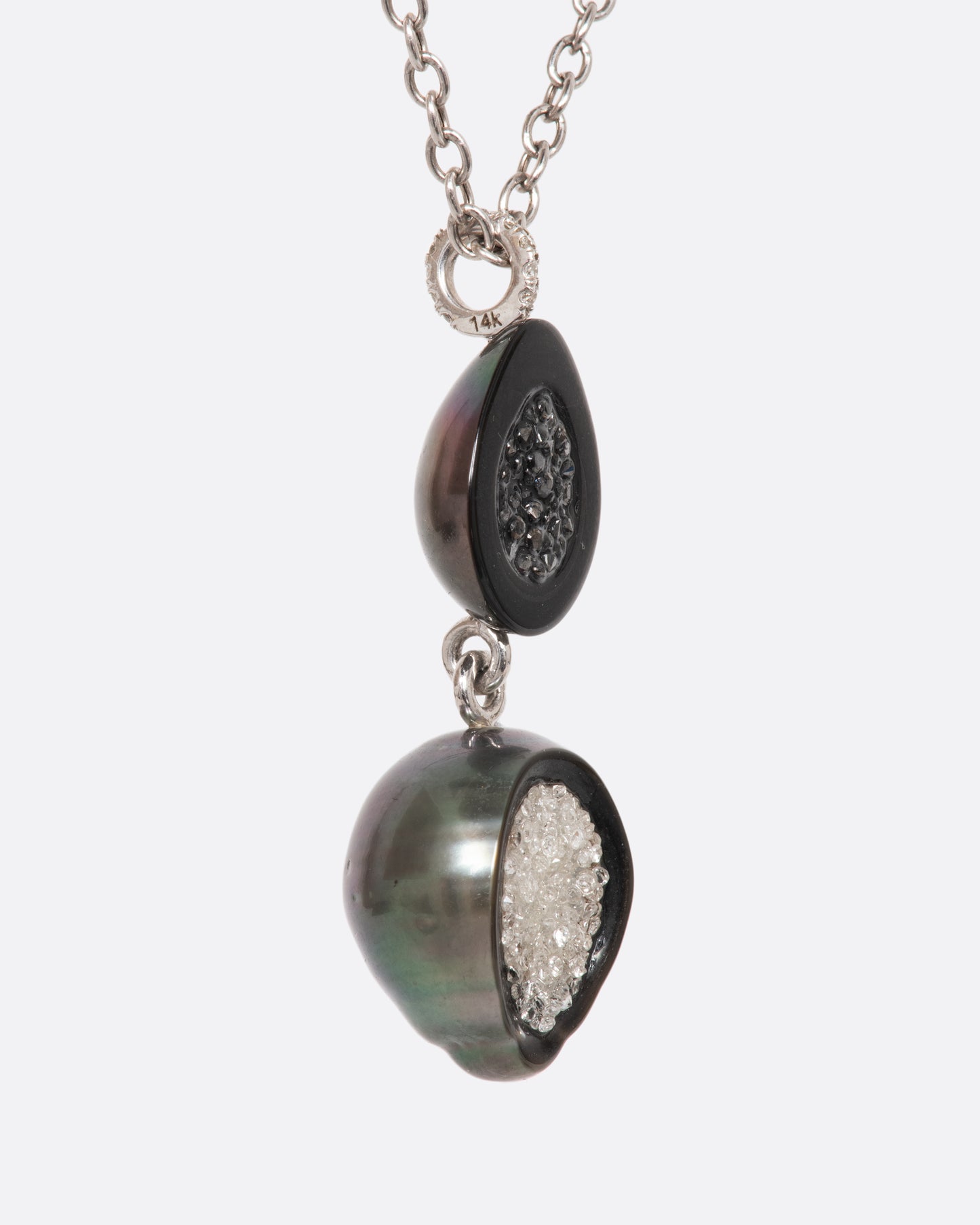 A white gold necklace with a double tiered Tahitian pearl pendant lined with black and white diamonds and a pave diamond bail. View from the side.