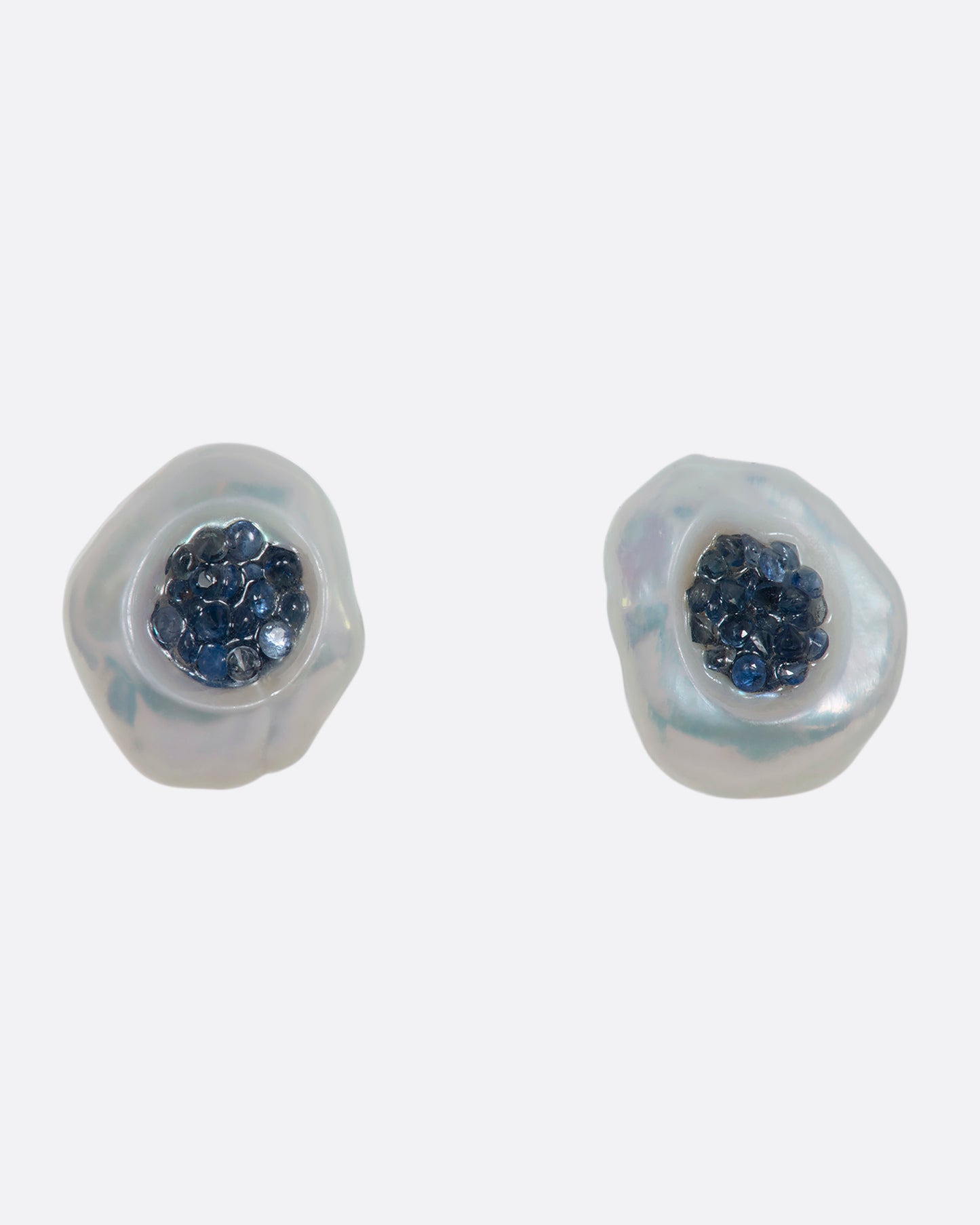 A pair of yellow gold earrings with hollowed out pearls filled with sapphires. Shown from the front.