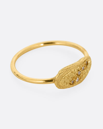 A yellow gold ring with a textural finish and five diamonds. Shown from the side.