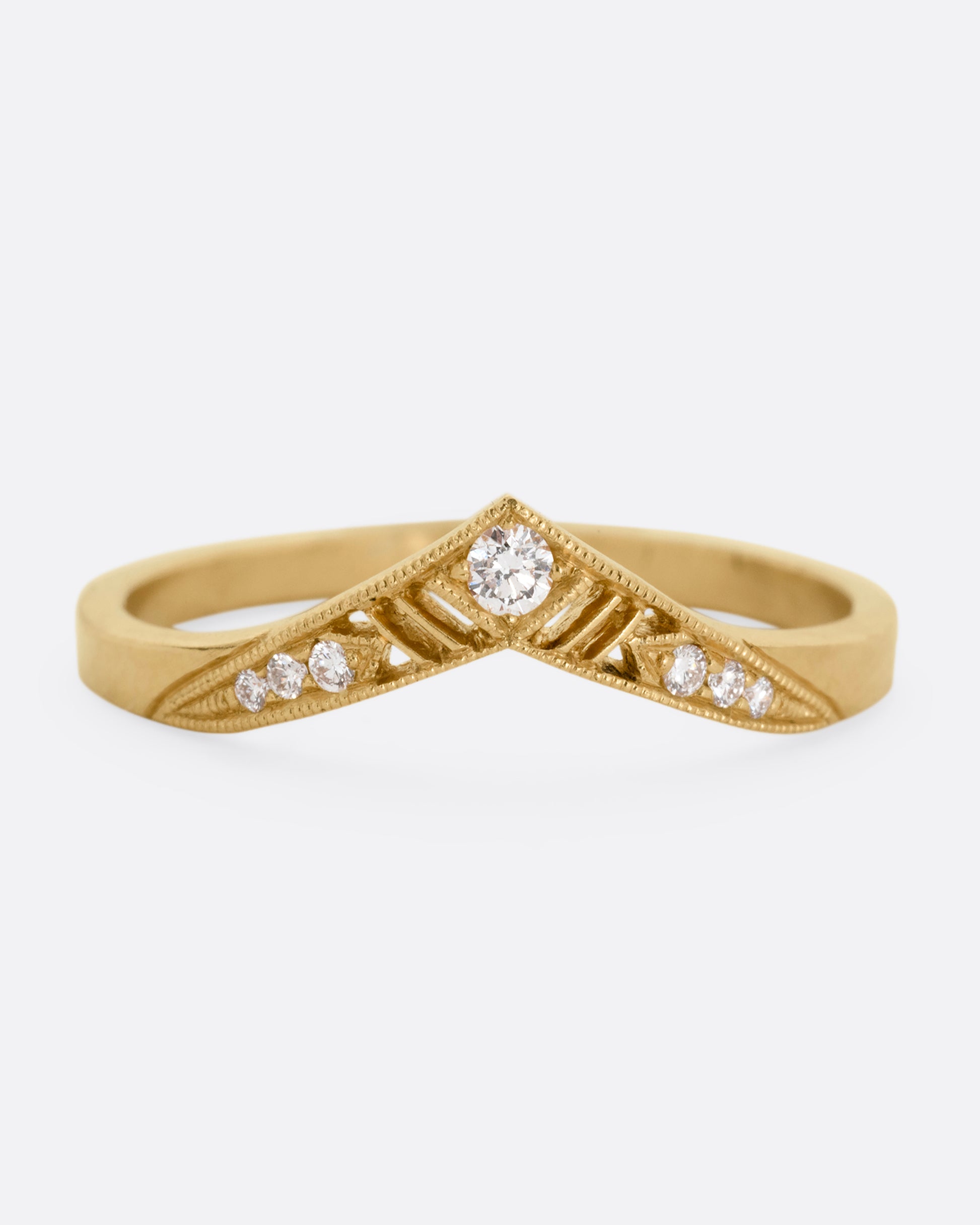 A slightly pointed yellow gold ring with diamonds and cutouts shown from the from the front.