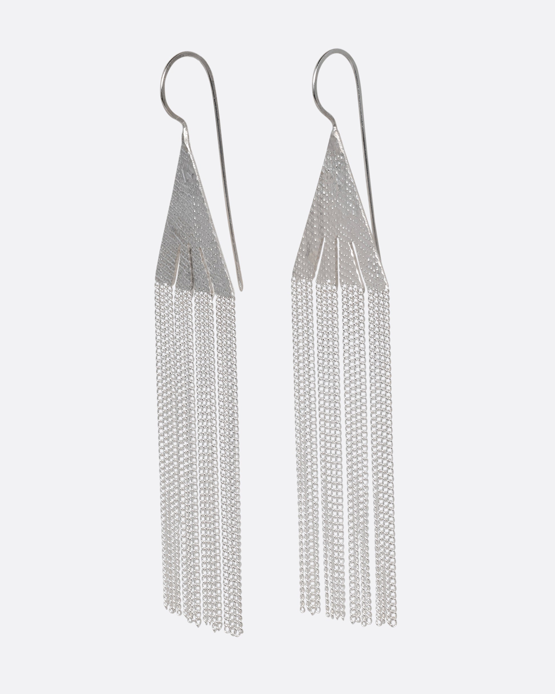 A pair of silver fringe earrings with triangular tops. Shown from the side.