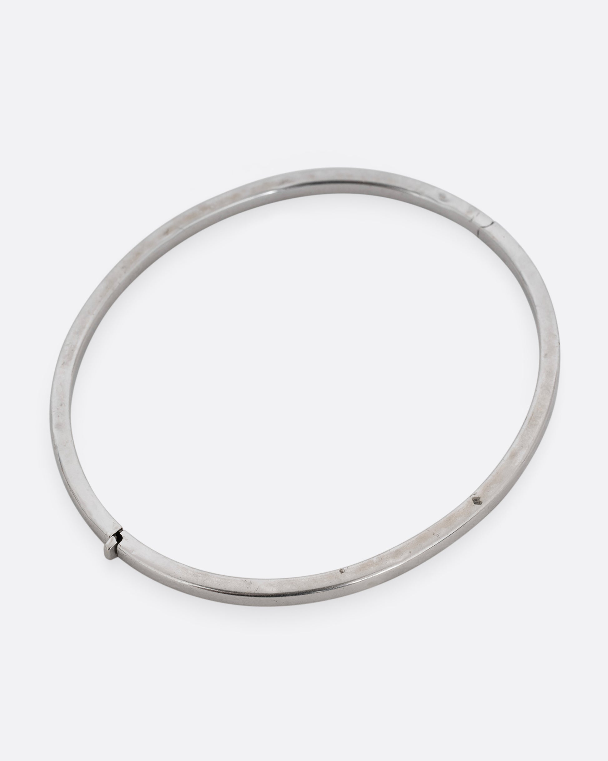 A silver hinged  bangle bracelet with squared edges. Shown from the top.