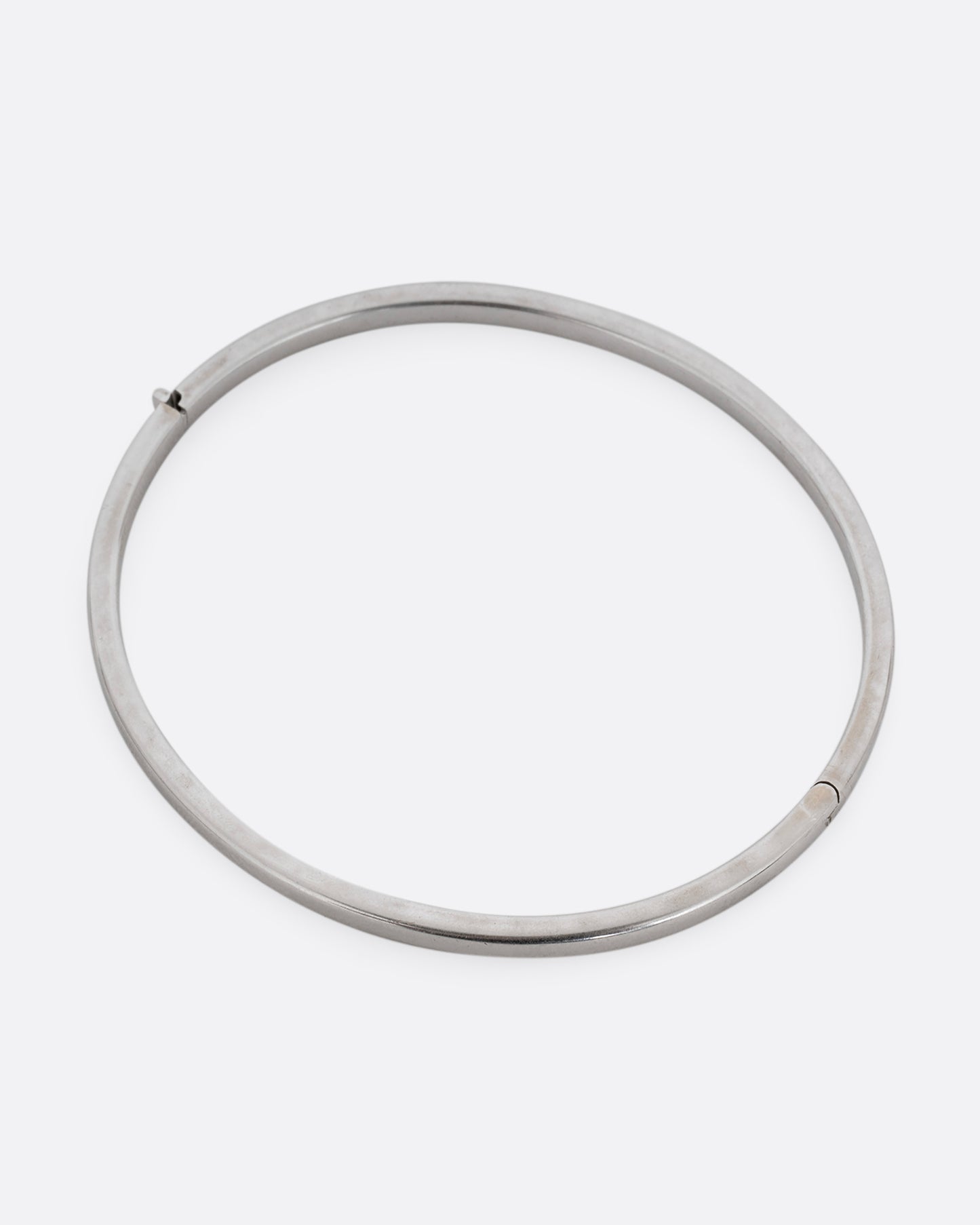 A silver hinged  bangle bracelet with squared edges. Shown from the top.
