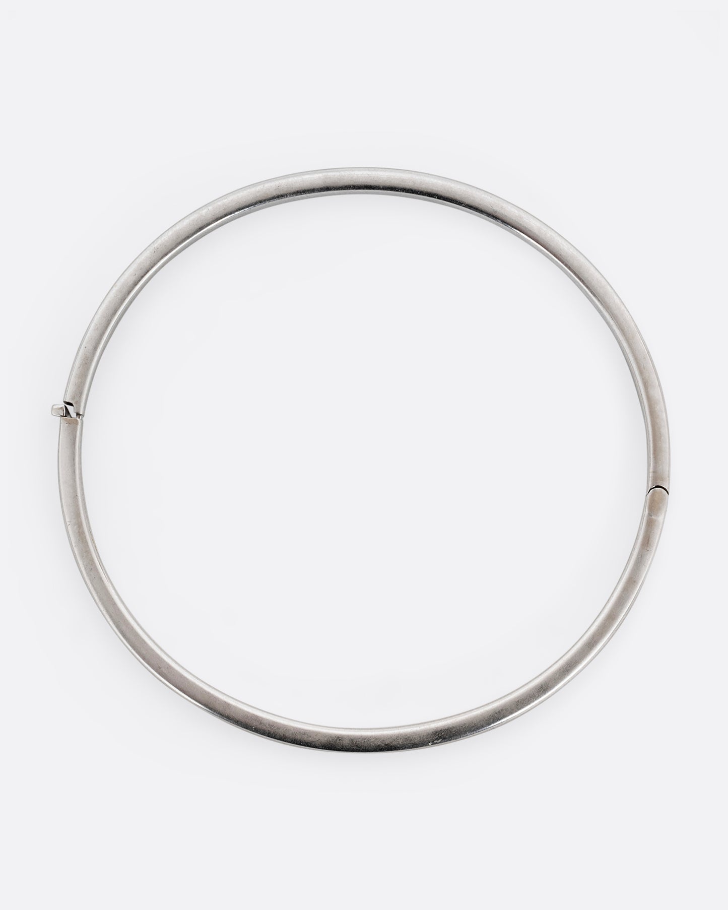 A silver hinged  bangle bracelet with squared edges. Shown from the top.