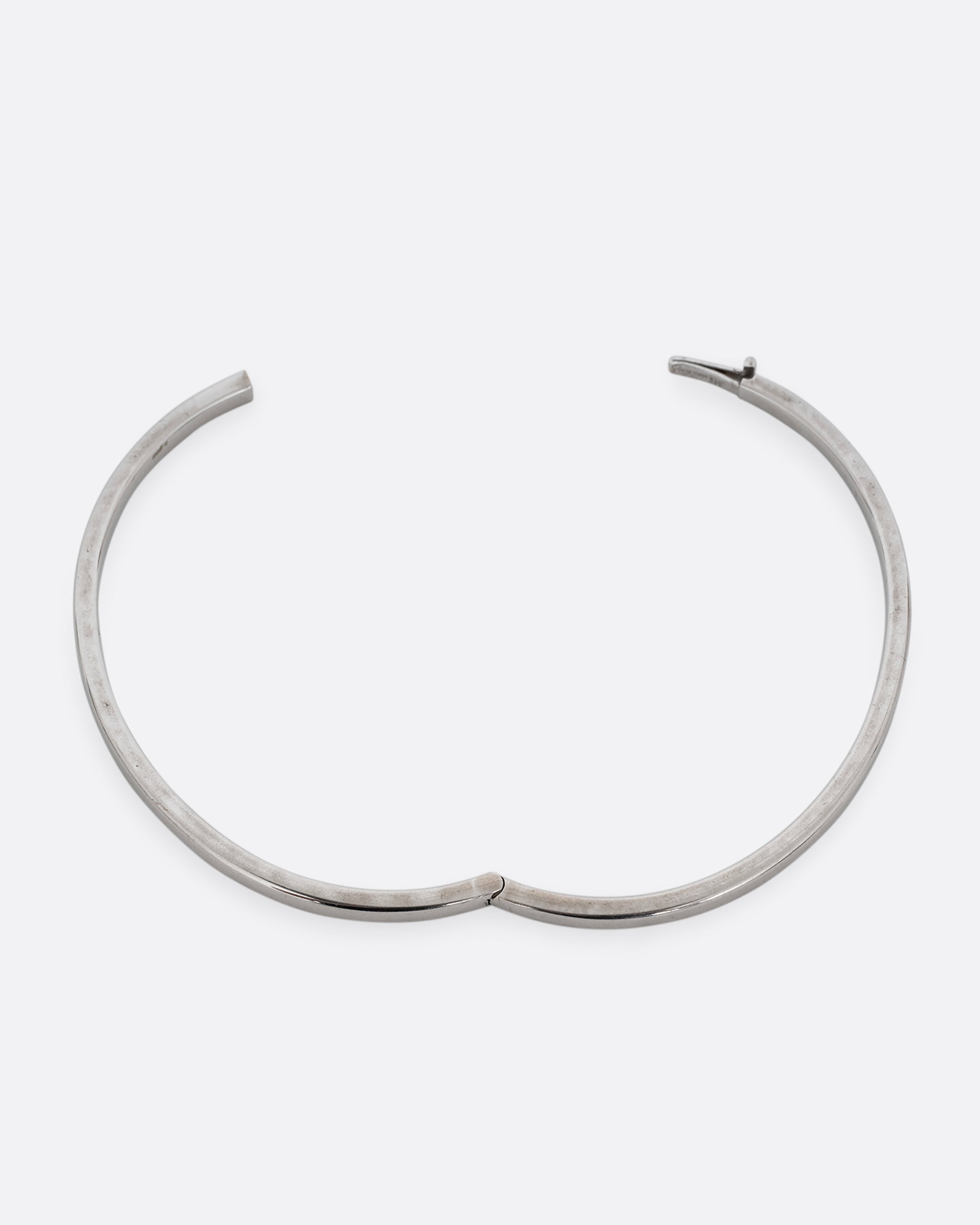 A silver hinged  bangle bracelet with squared edges. Shown open from the top.
