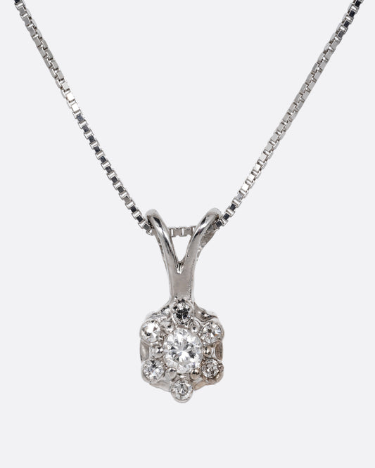 A white gold box chain necklace with a diamond studded flower shaped pendant. Shown from the front.