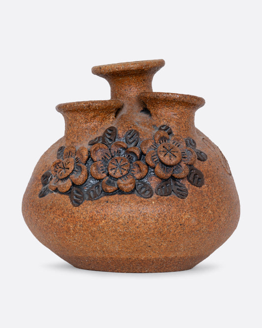A sand art pottery vase with three openings for flowers and a floral pattern along the front. Shown from the front.