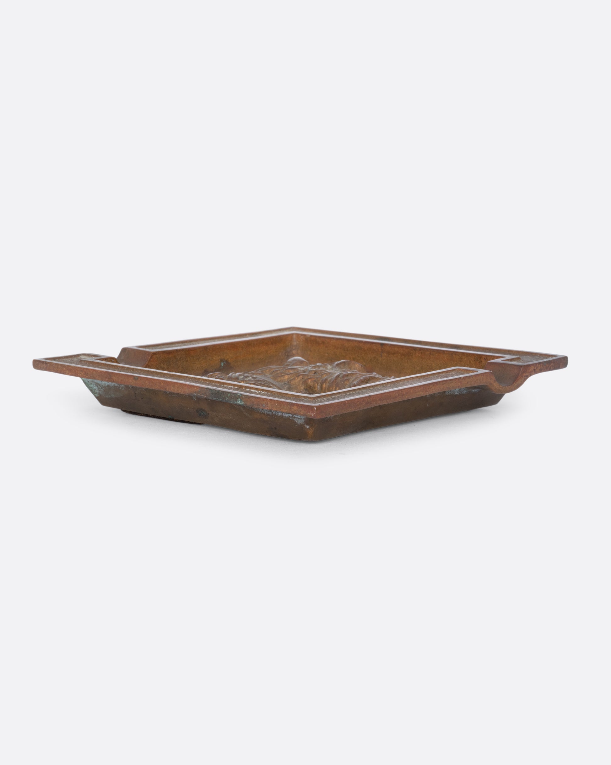 A square brass ashtray with a dunhill Scottie and a cork bottom. Shown from the side.