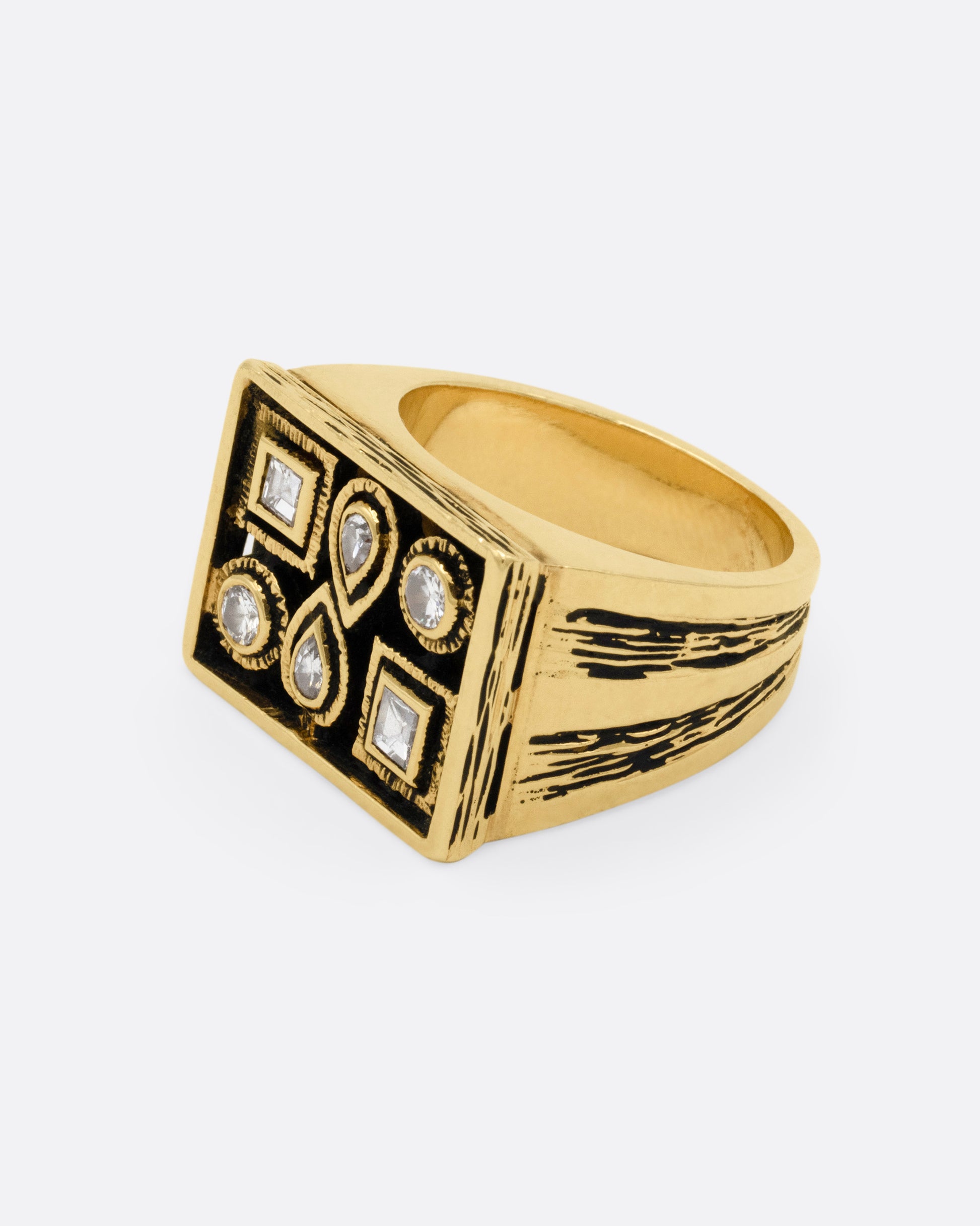 A rectangular yellow gold signet ring with mixed cut diamonds sand textured stone settings and shoulders, shown from the side.