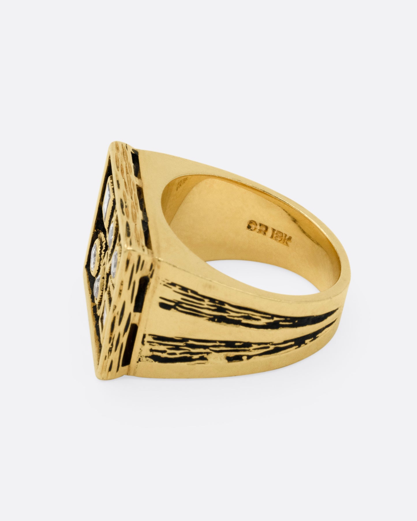 A rectangular yellow gold signet ring with mixed cut diamonds sand textured stone settings and shoulders, shown from the side.