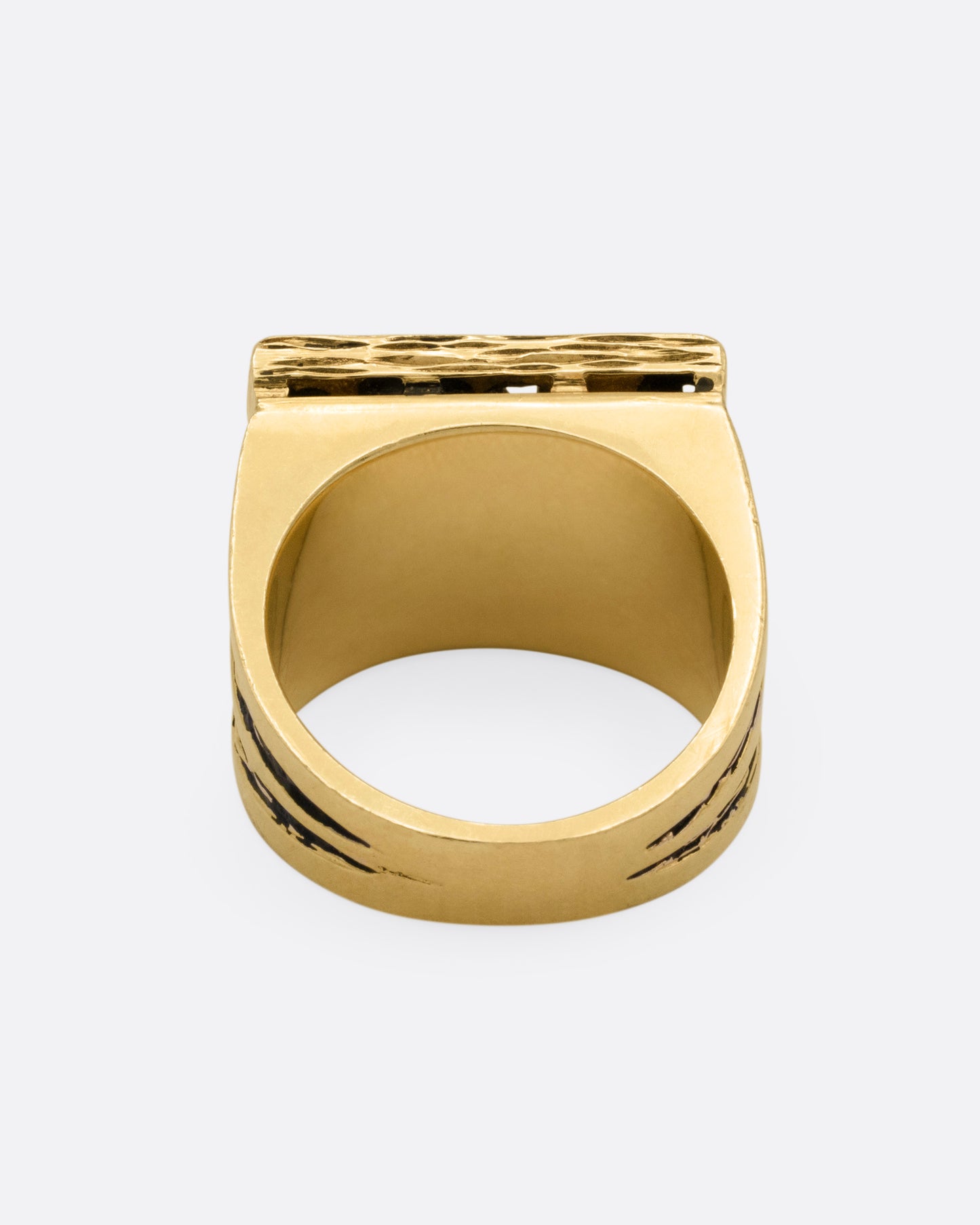 A rectangular yellow gold signet ring with mixed cut diamonds sand textured stone settings and shoulders, shown from the back.