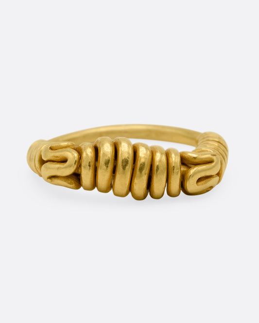 A yellow gold ring with a coiled spiral design across the face and shoulders, shown from the front.
