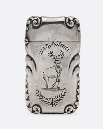 A silver match safe with a deer among scroll work, shown from the front.