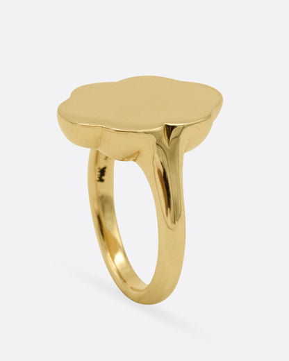A yellow gold signet ring with scalloped edges, shown from the side standing up.