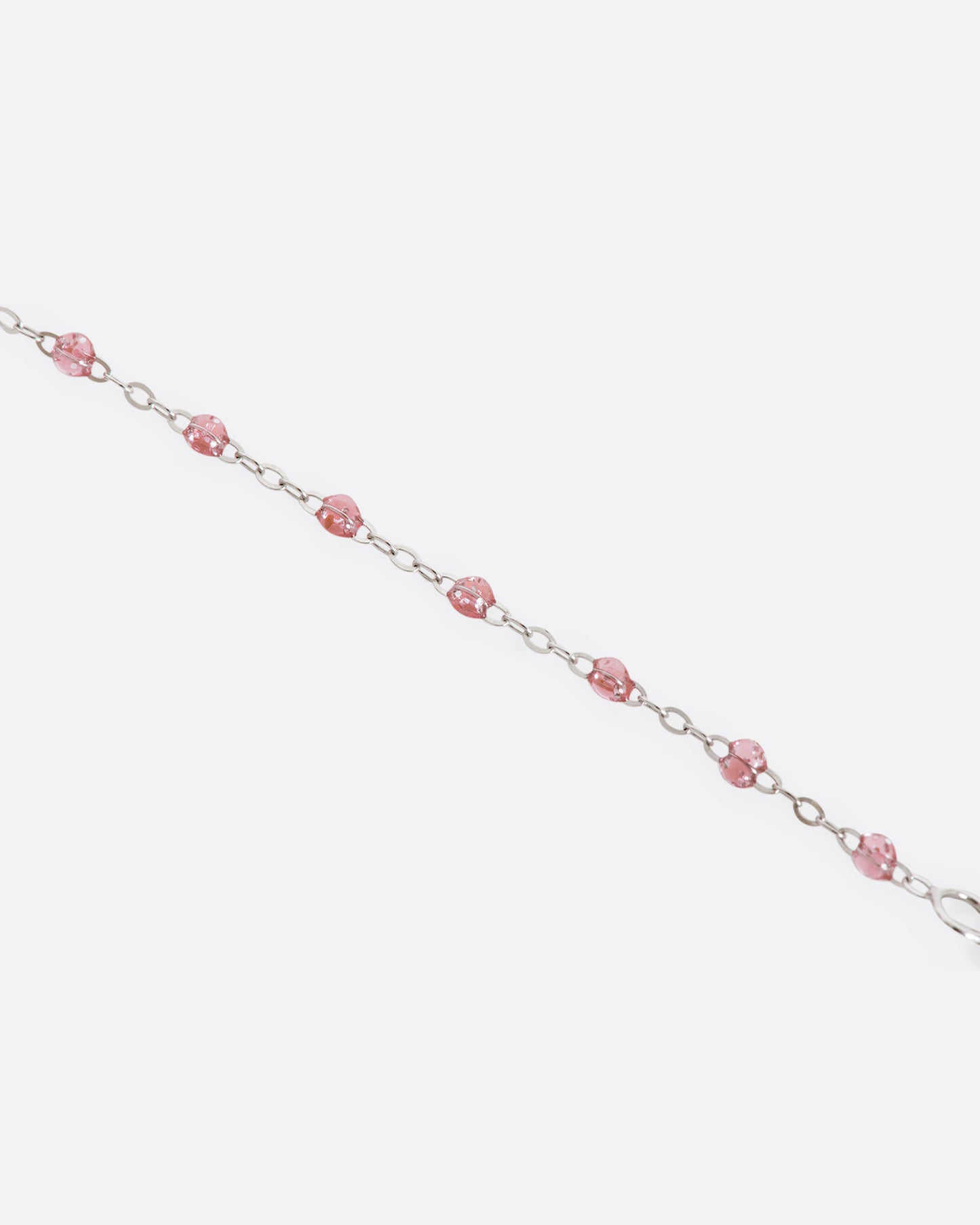 A white gold bracelet with rose pink glitter resin beads and a pave diamond disc and the center. View up close of beads.