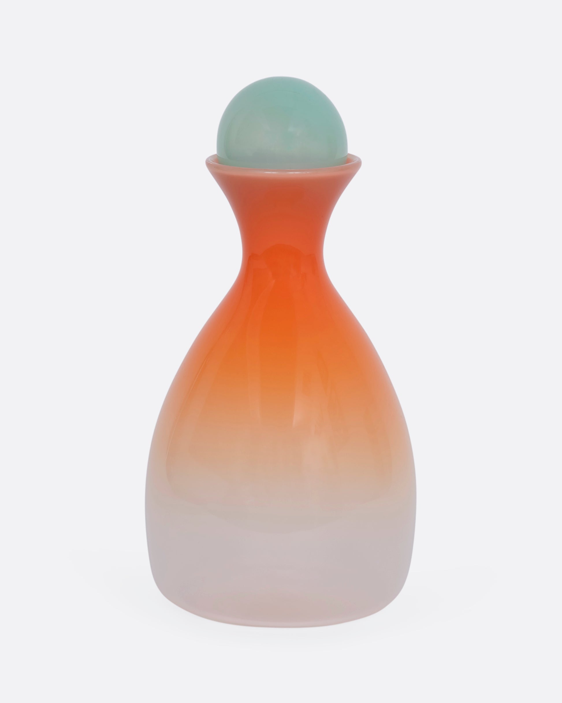 An ombre orange decanter with a mint green sphere stopper. View from the front.