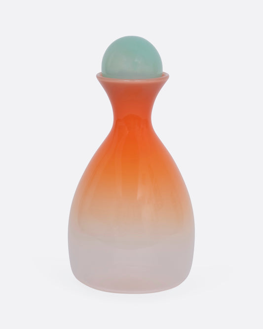 An ombre orange decanter with a mint green sphere stopper. View from the front.