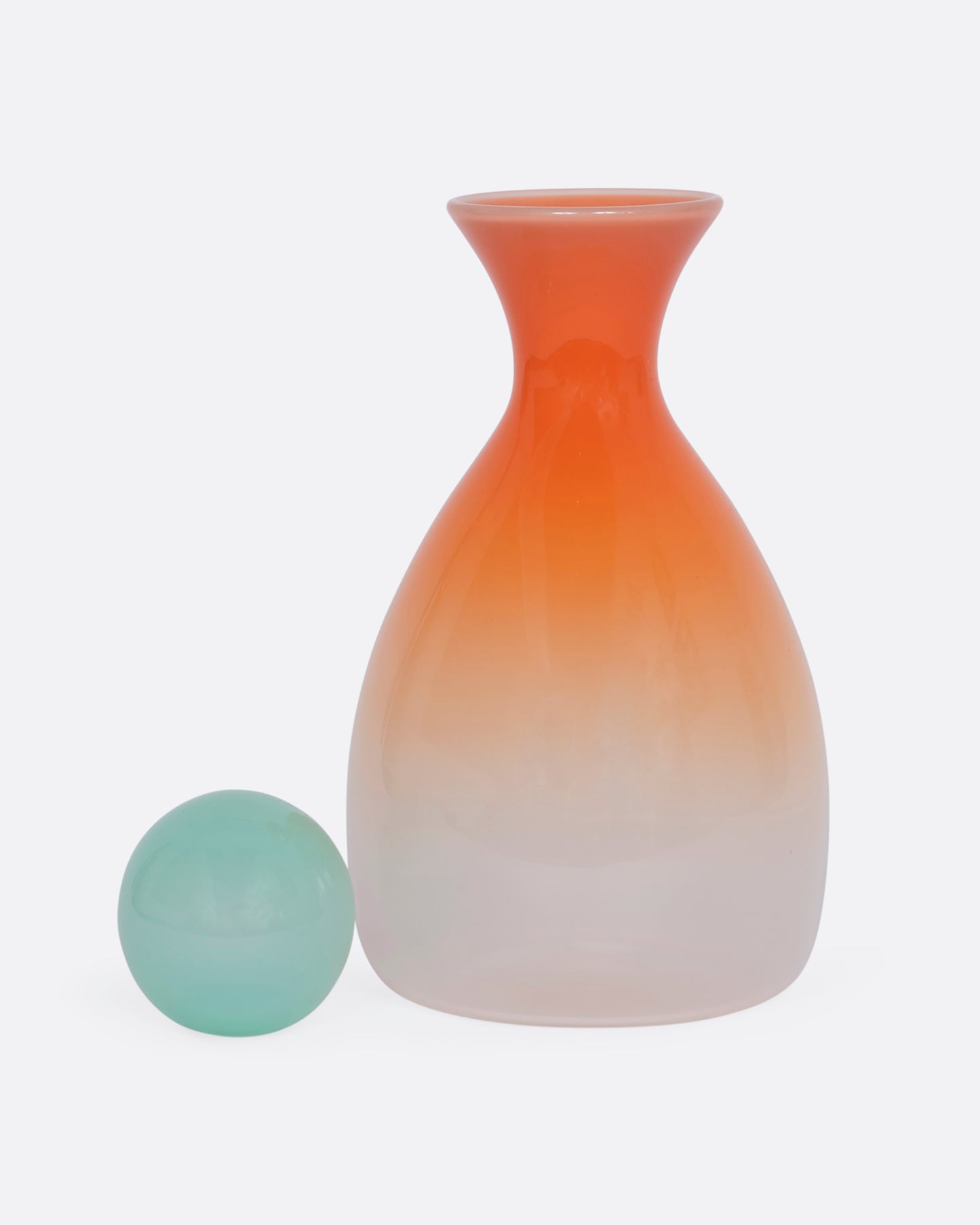 An ombre orange decanter with a mint green sphere stopper. View with the stopper removed.