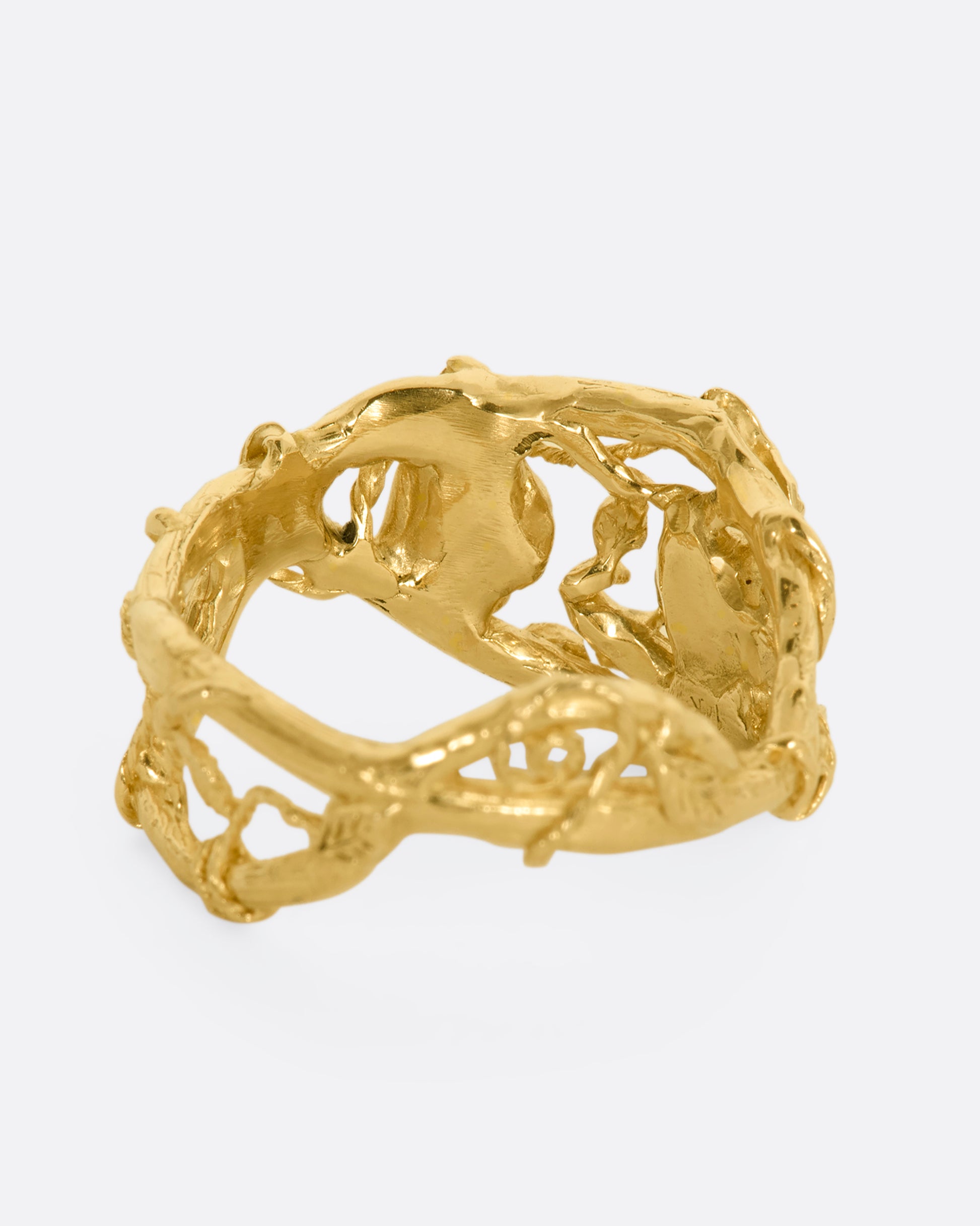 A yellow gold momento mori ring with organic branch and vine motif, featuring two skulls. View from the back.