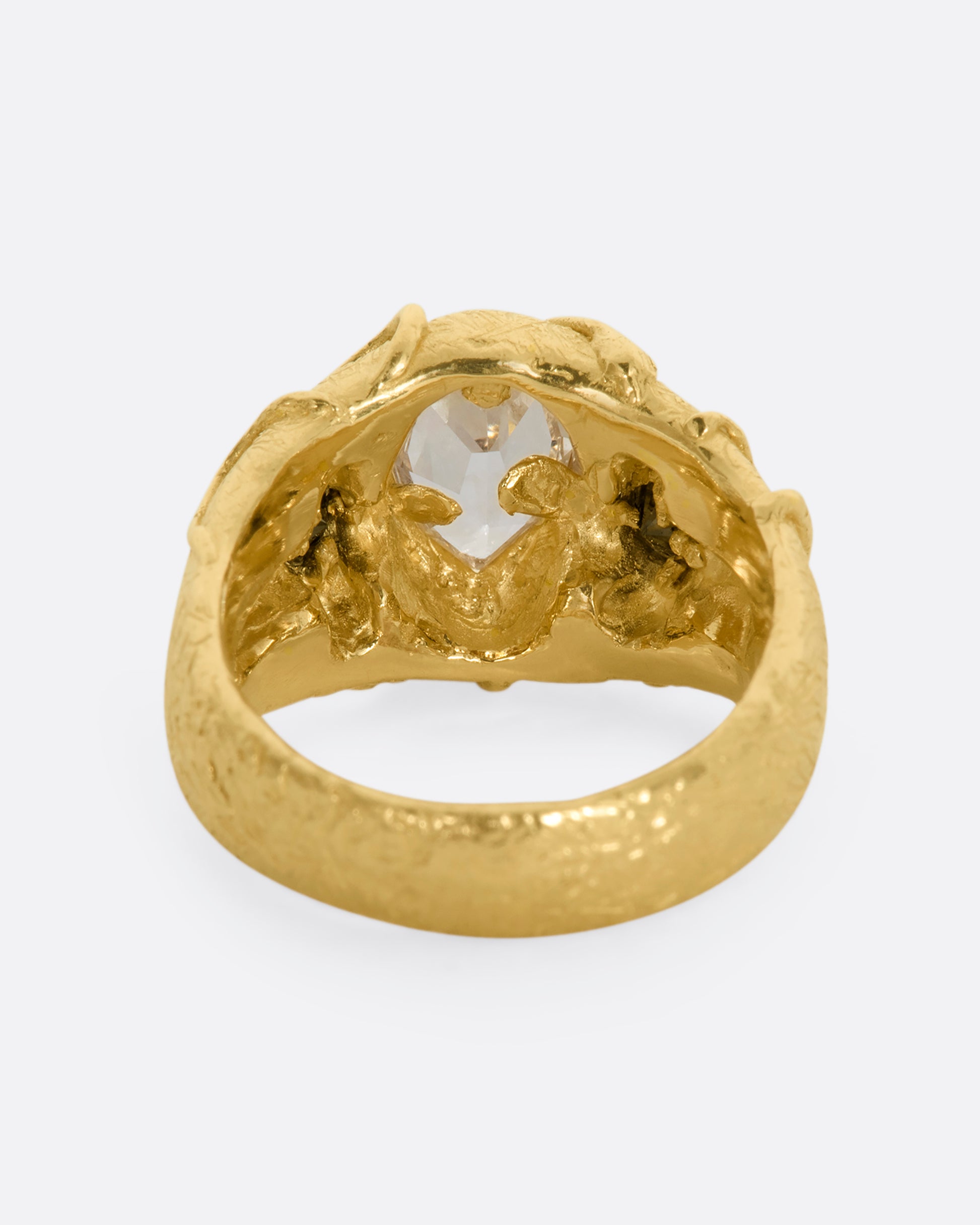 A chunky yellow gold ring with a vine motif that looks like it's grown over the fancy step cut sapphire at the center and the brilliant black diamonds. View from the back.