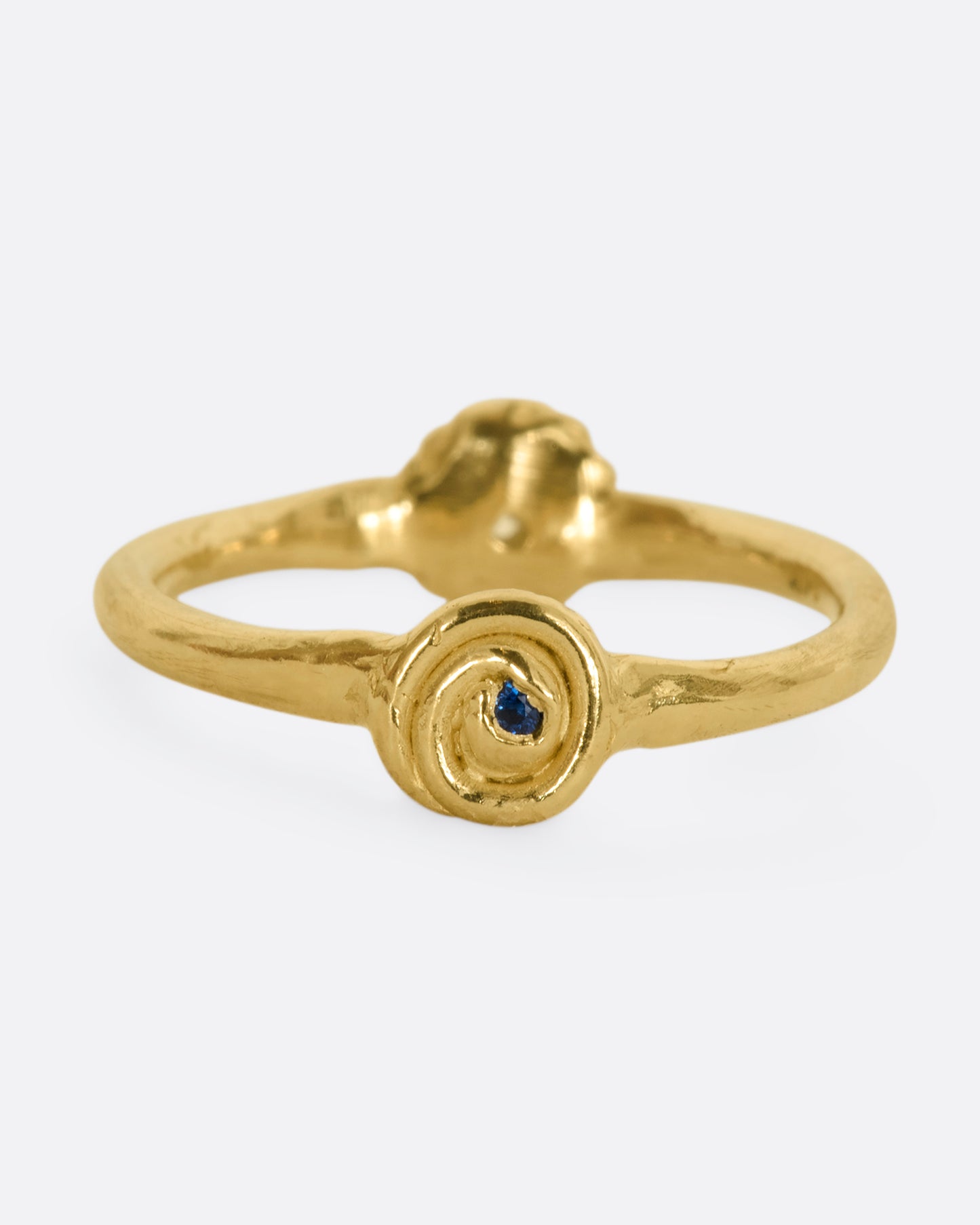 A yellow gold ring with a rosebud motif on either side, one with a white sapphire, the other with a blue sapphire for wear two ways. View from the blue sapphire side.