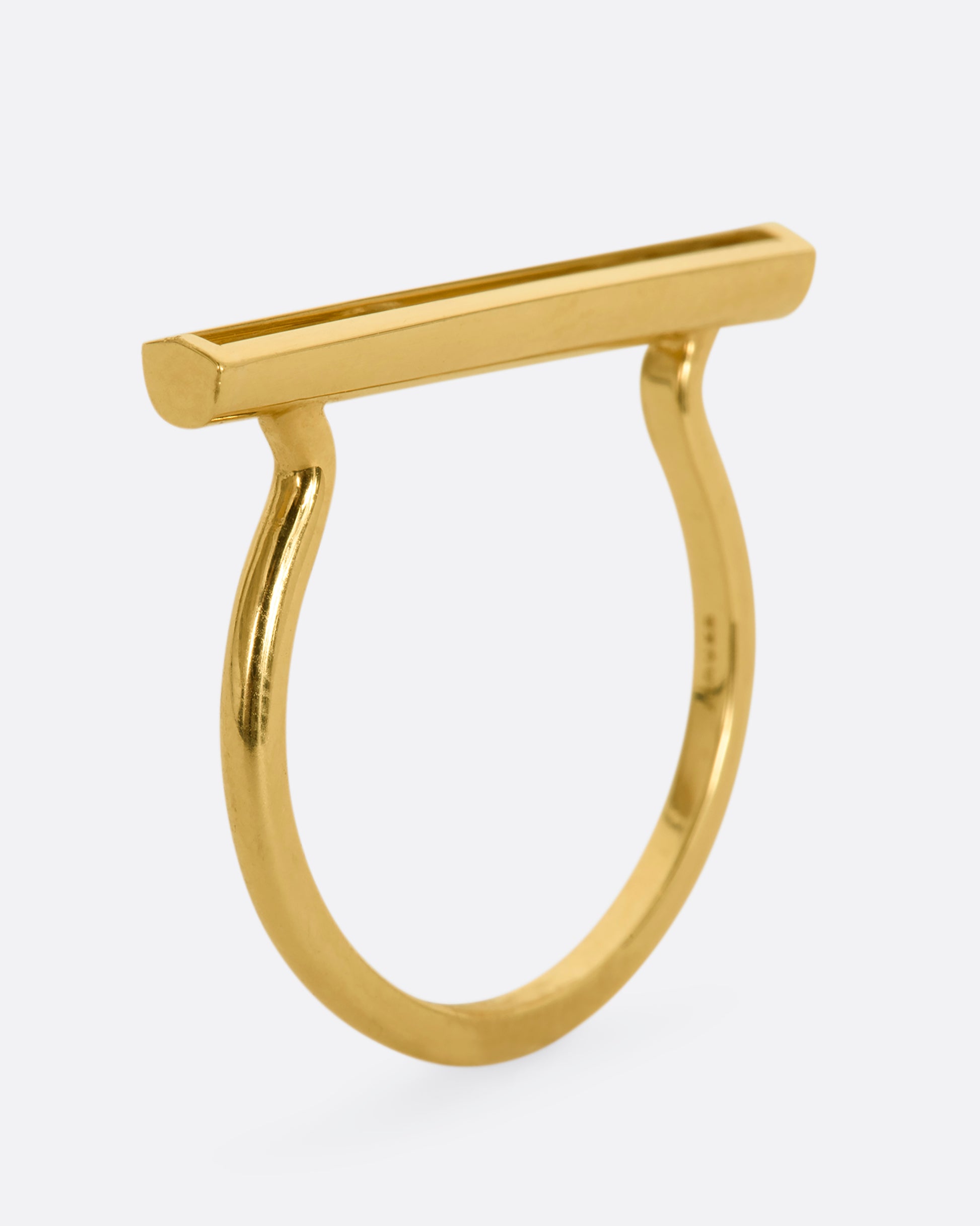 A polished yellow gold ring with a rectangular face that holds three channel set sliding diamonds. View from the side, standing.