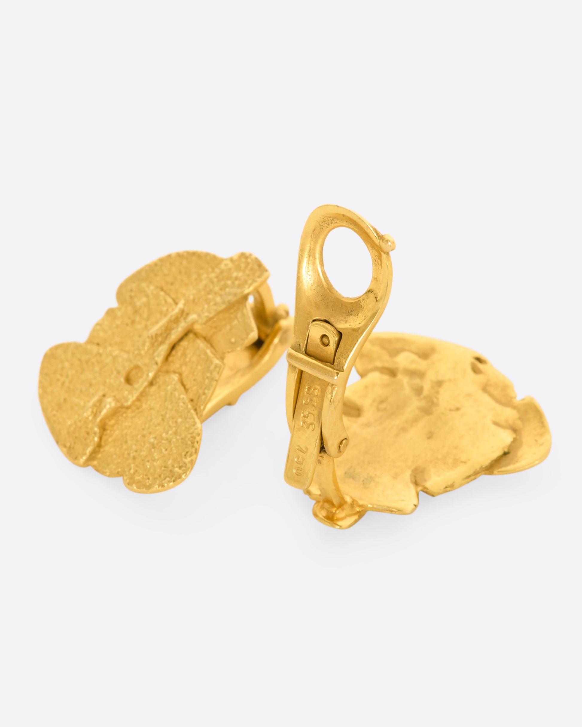 Yellow gold textured three tier clip on earrings. View laying flat.