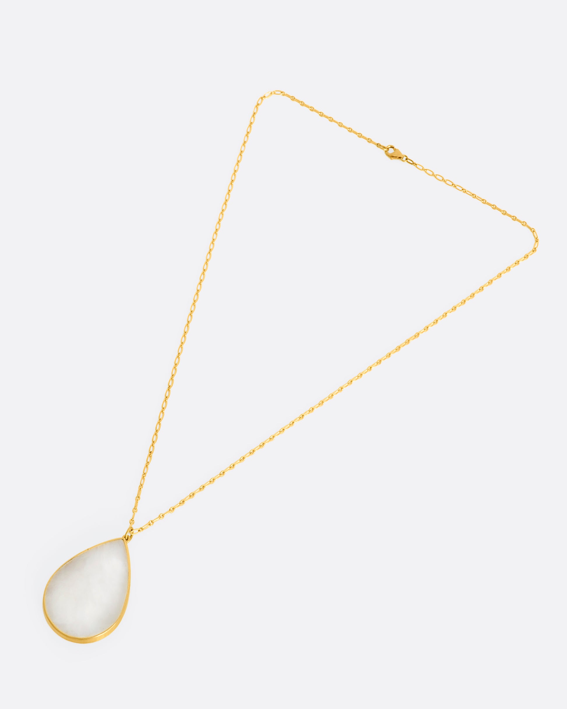 A tear drop shaped moonstone in a yellow gold bezel setting hanging from a yellow gold chain. View on the entire necklace from above.