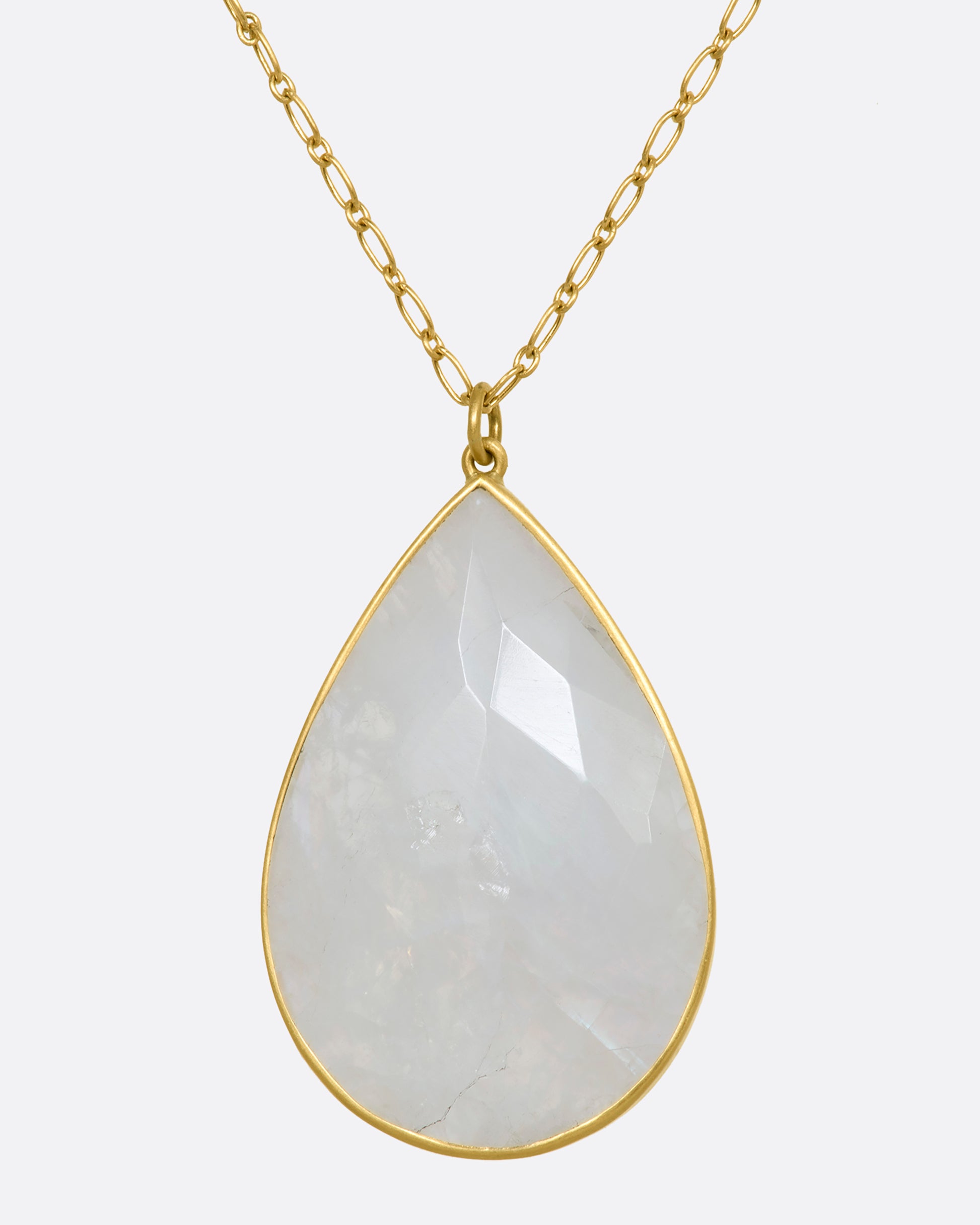 A tear drop shaped moonstone in a yellow gold bezel setting hanging from a yellow gold chain. View up close from the front.