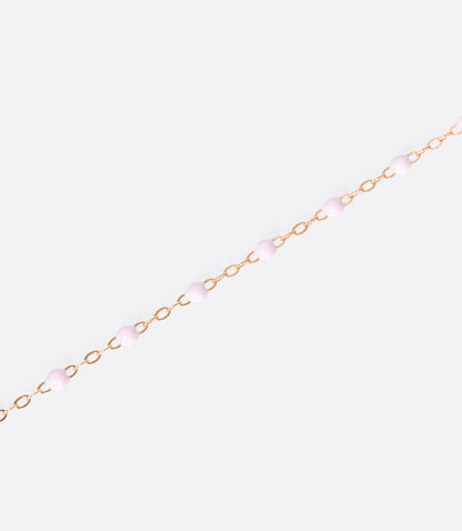 A close up view of a yellow gold cable chain bracelet with baby pink resin droplets. 