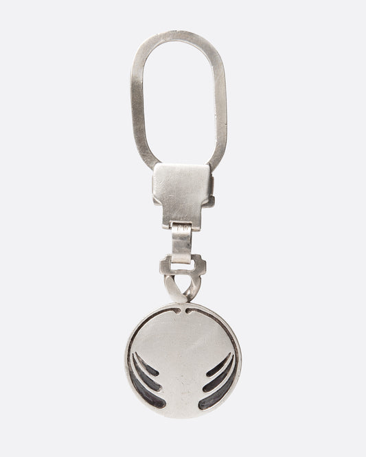 A silver key chain with a circular charm with engraved whiplash curves, shown from the front.