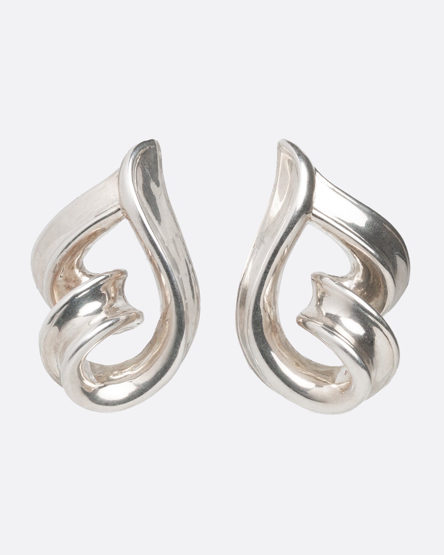 A pair of twisting silver loop earrings shown from the front.